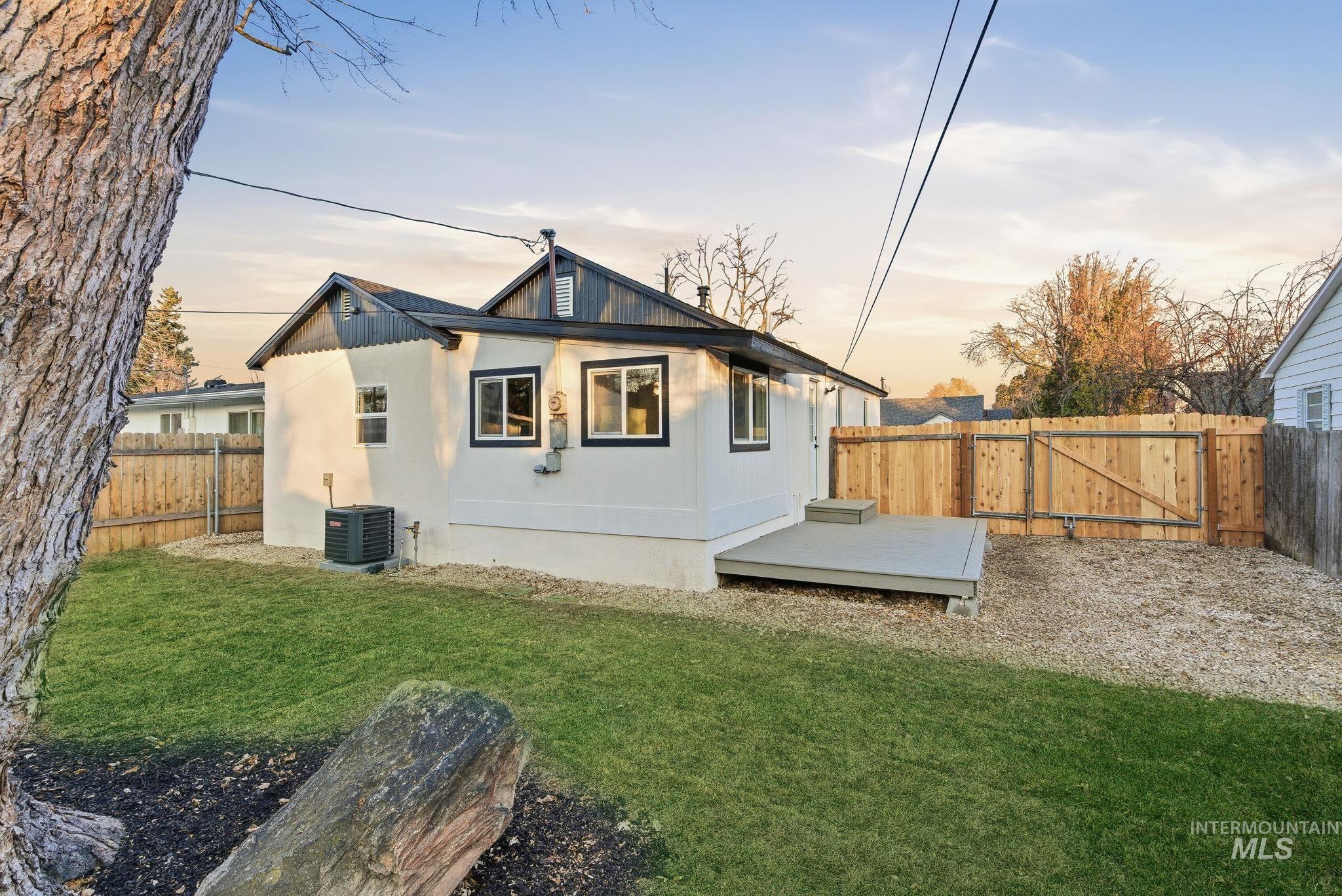 Back of property at dusk with a fenced backyard, a deck, and a gate