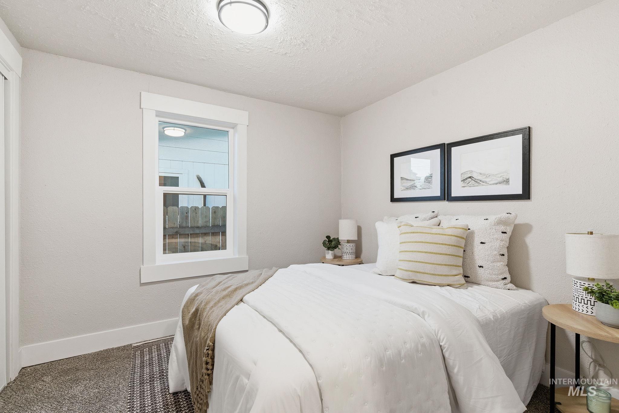 Bedroom with a textured ceiling, carpet floors, and a textured wall