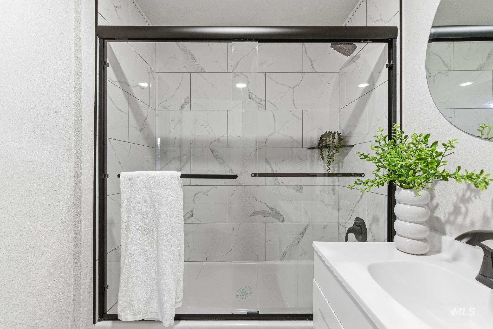 Full bathroom with vanity, an enclosed shower, and a textured wall