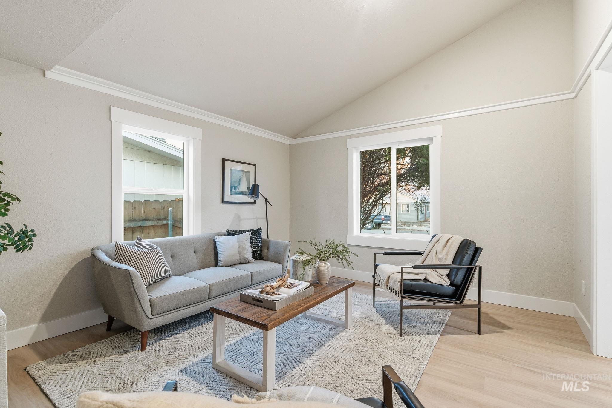 Living area with light wood finished floors, vaulted ceiling, and crown molding