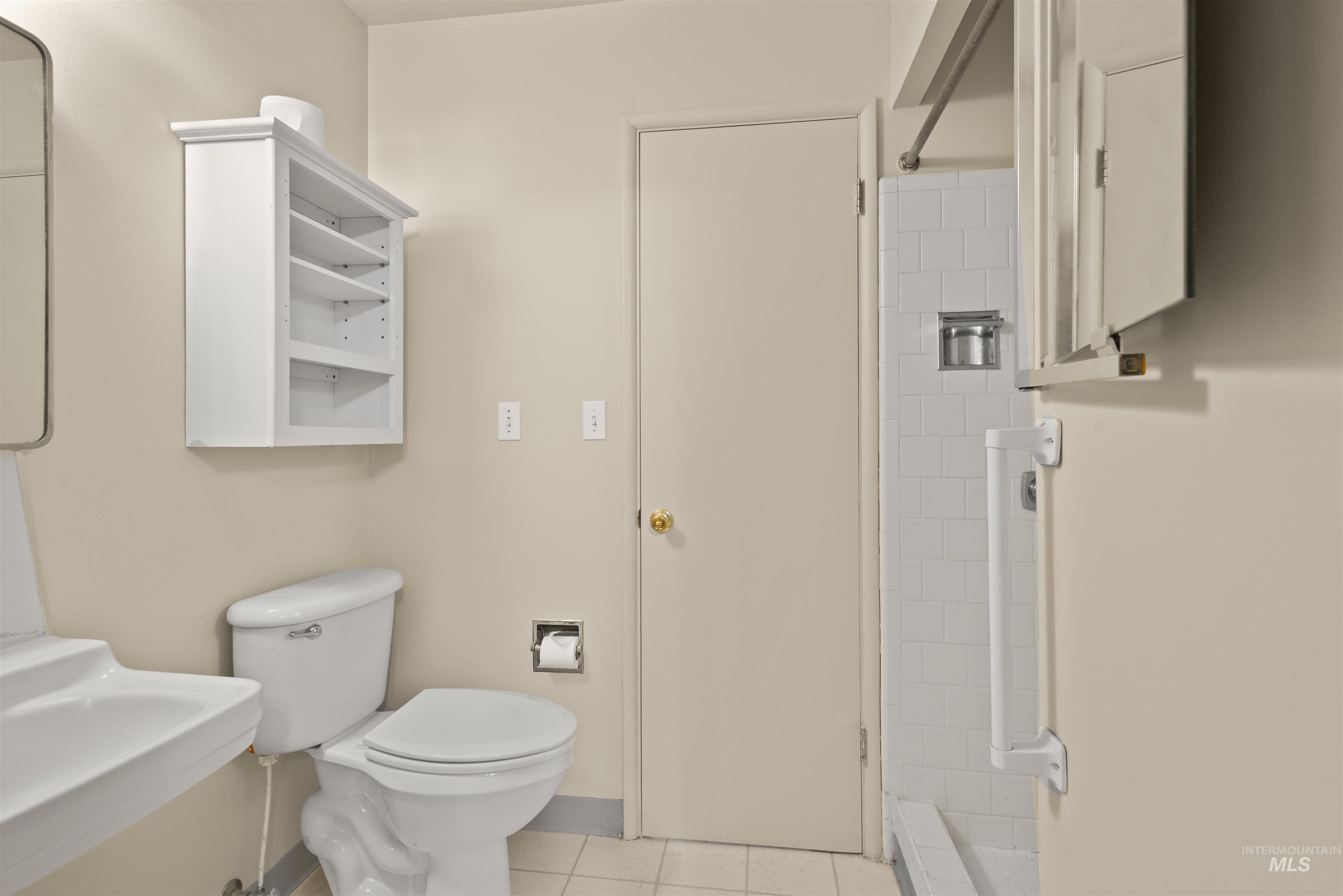 Bathroom with light tile patterned flooring and a stall shower