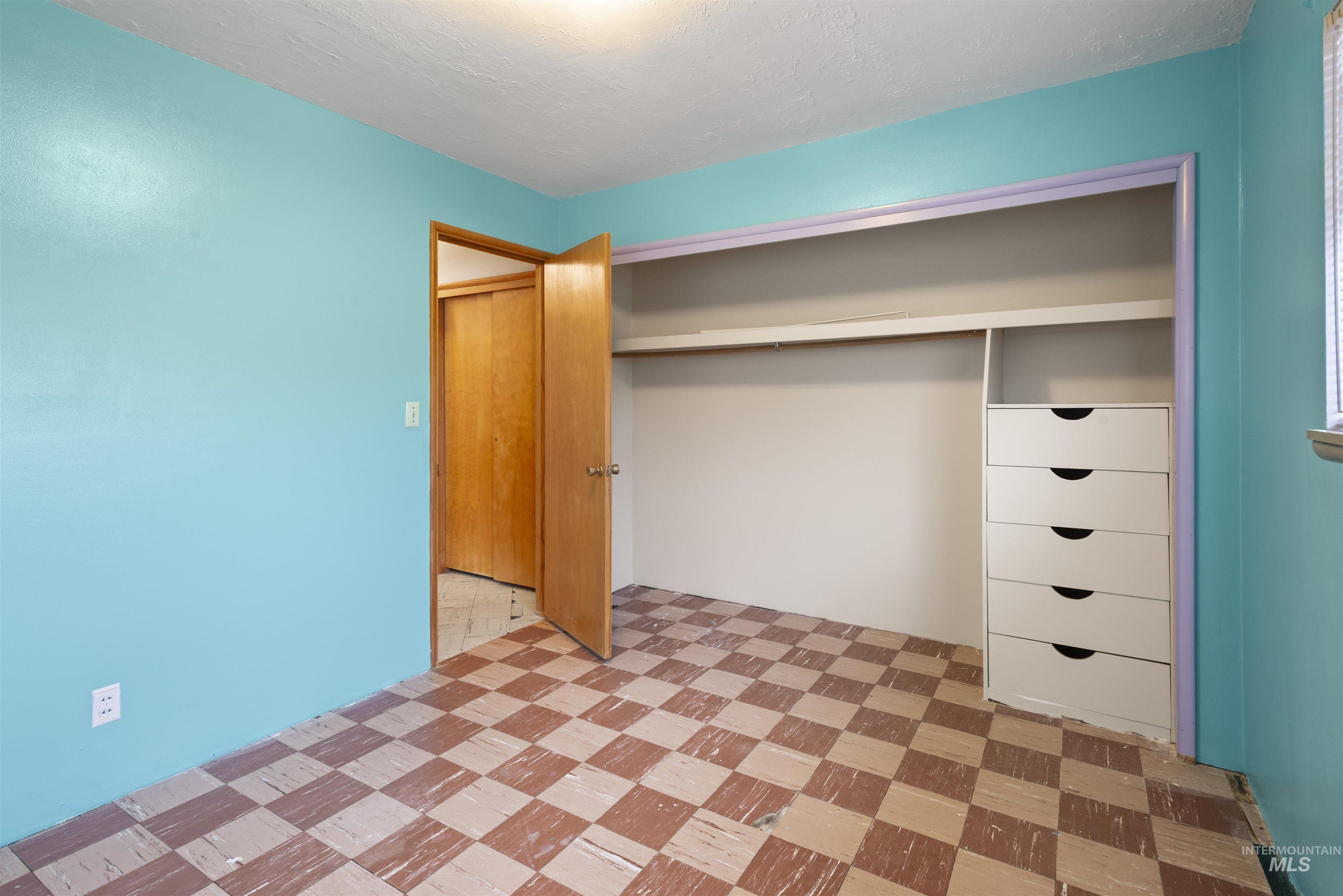 Unfurnished bedroom featuring a closet, light flooring, and a textured ceiling