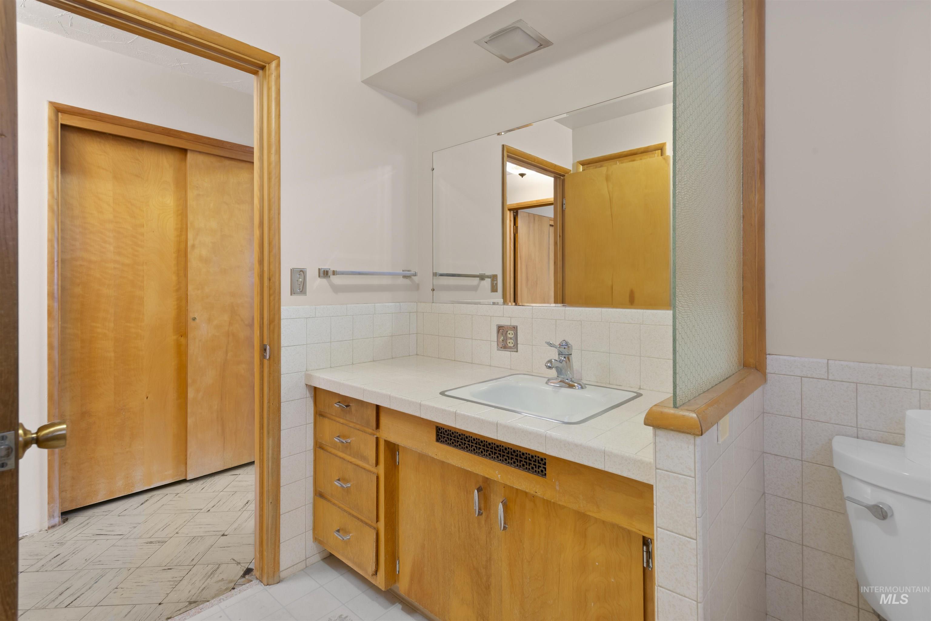 Bathroom with tile walls, vanity, wainscoting, and light floors