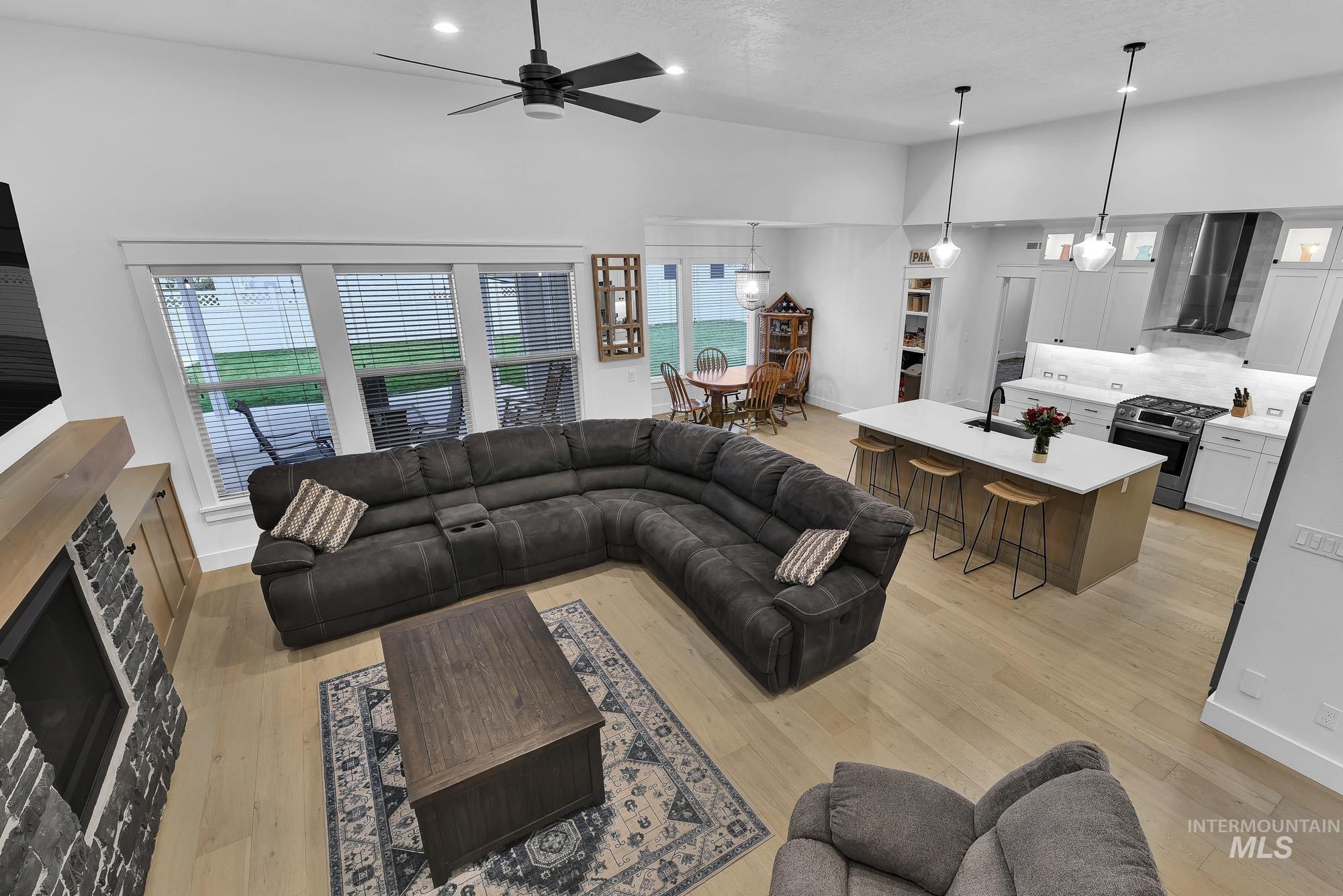 Living area with light wood-type flooring, ceiling fan, recessed lighting, a textured ceiling, and a high ceiling