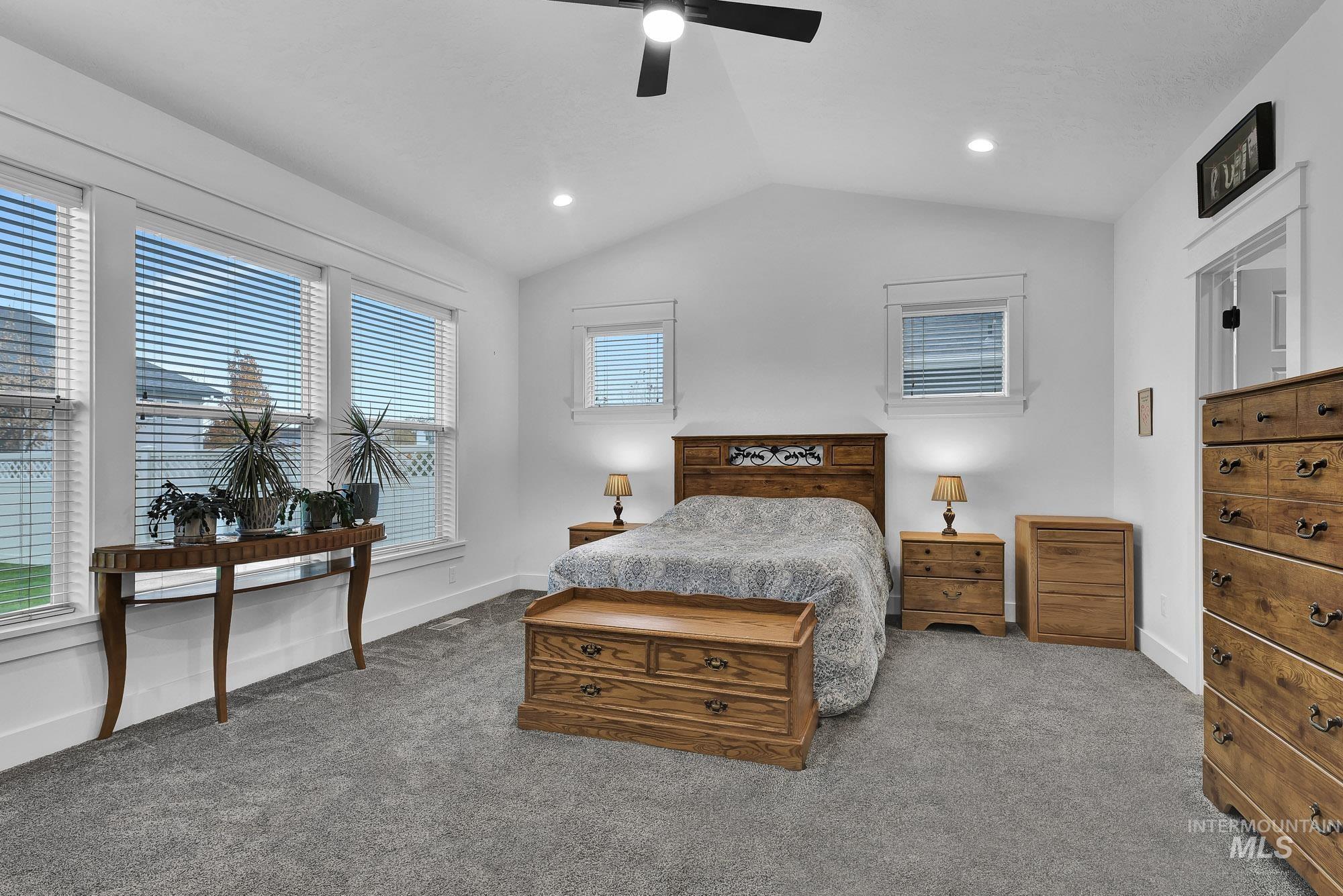 Carpeted bedroom with vaulted ceiling and ceiling fan