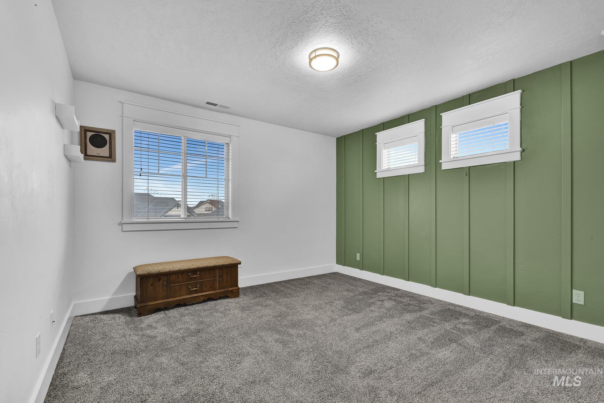 Spare room featuring plenty of natural light, dark colored carpet, and a textured ceiling