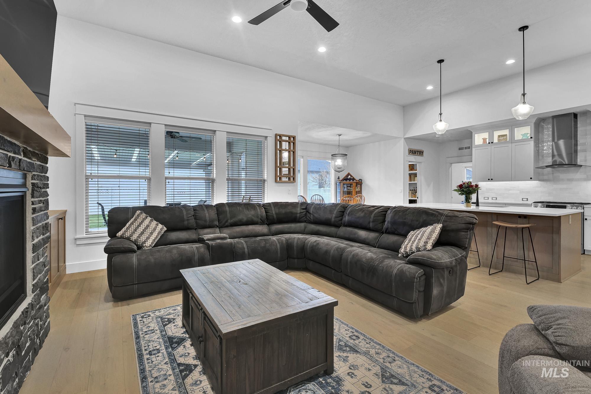 Living area with a fireplace, light wood finished floors, recessed lighting, and ceiling fan
