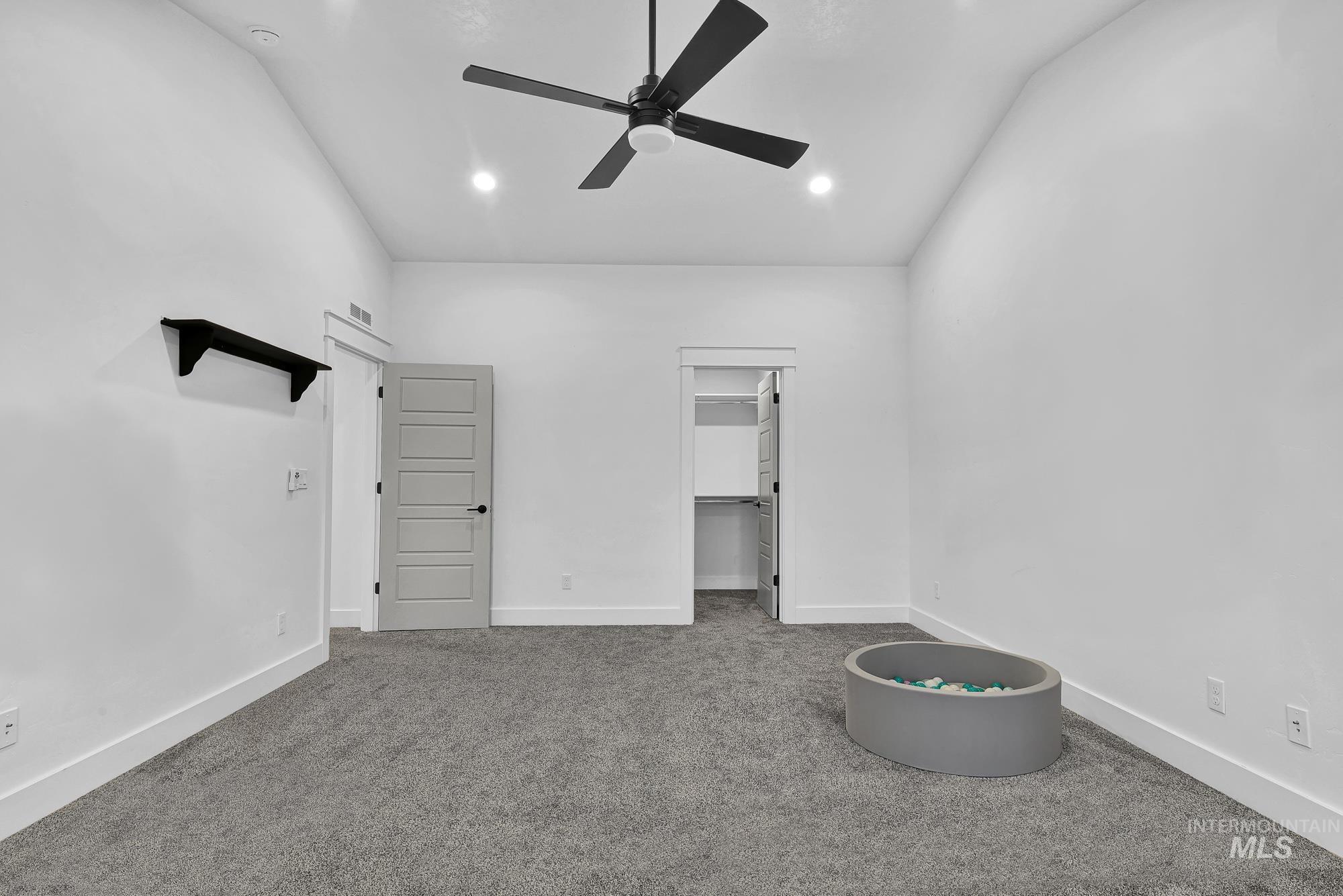 Unfurnished bedroom featuring light colored carpet, a spacious closet, recessed lighting, a ceiling fan, and lofted ceiling