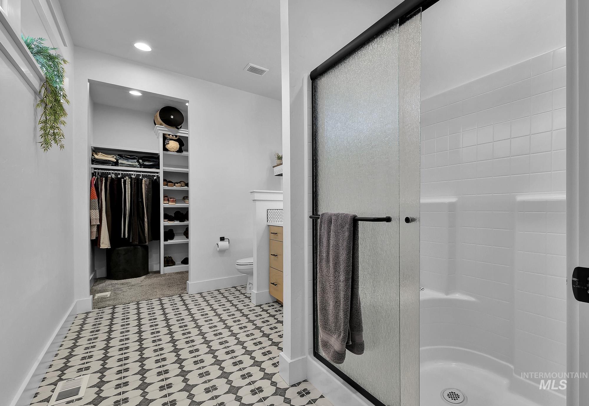 Full bathroom featuring a spacious closet, a stall shower, recessed lighting, light flooring, and vanity