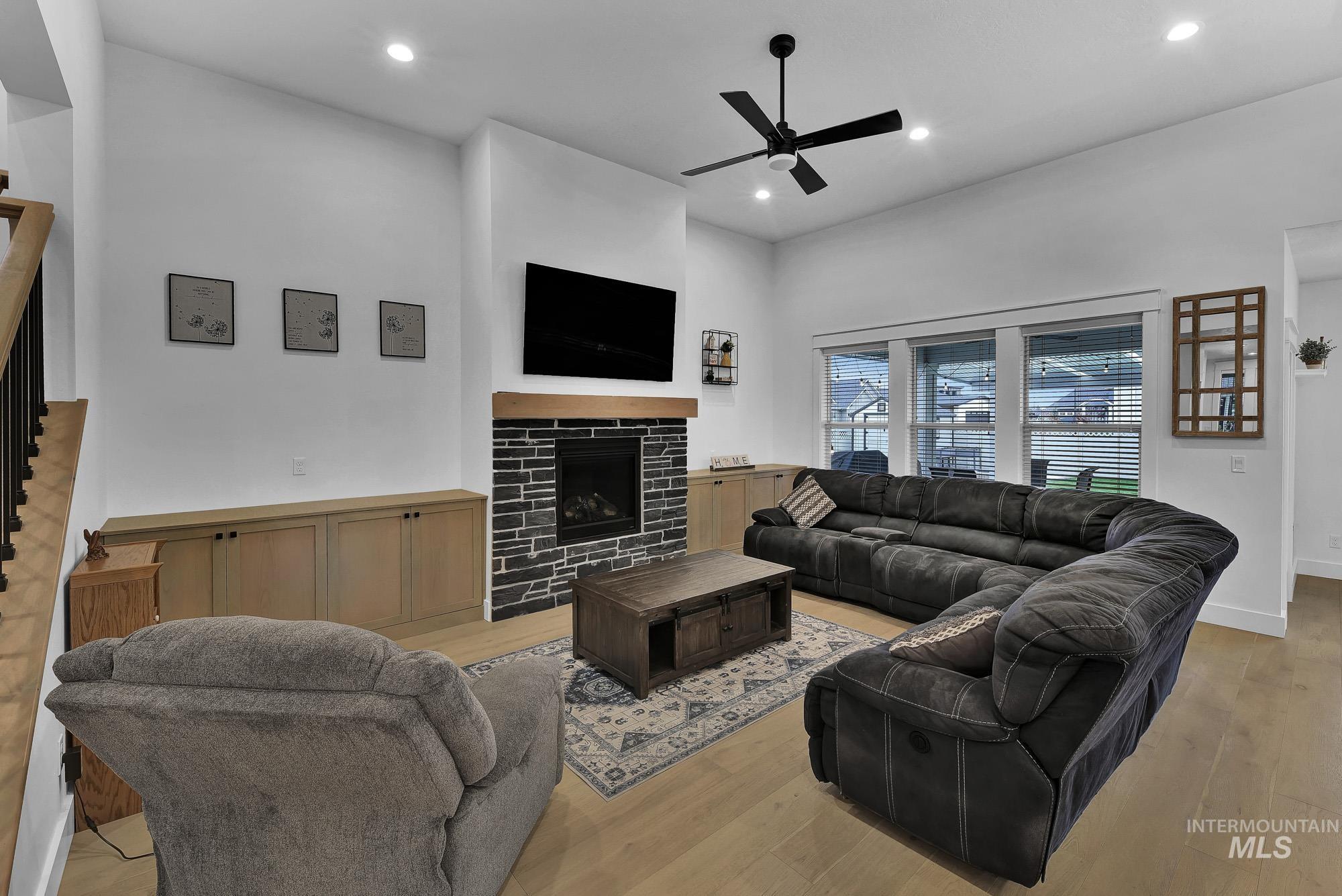Living area with a tiled fireplace, light wood-style floors, recessed lighting, and a ceiling fan