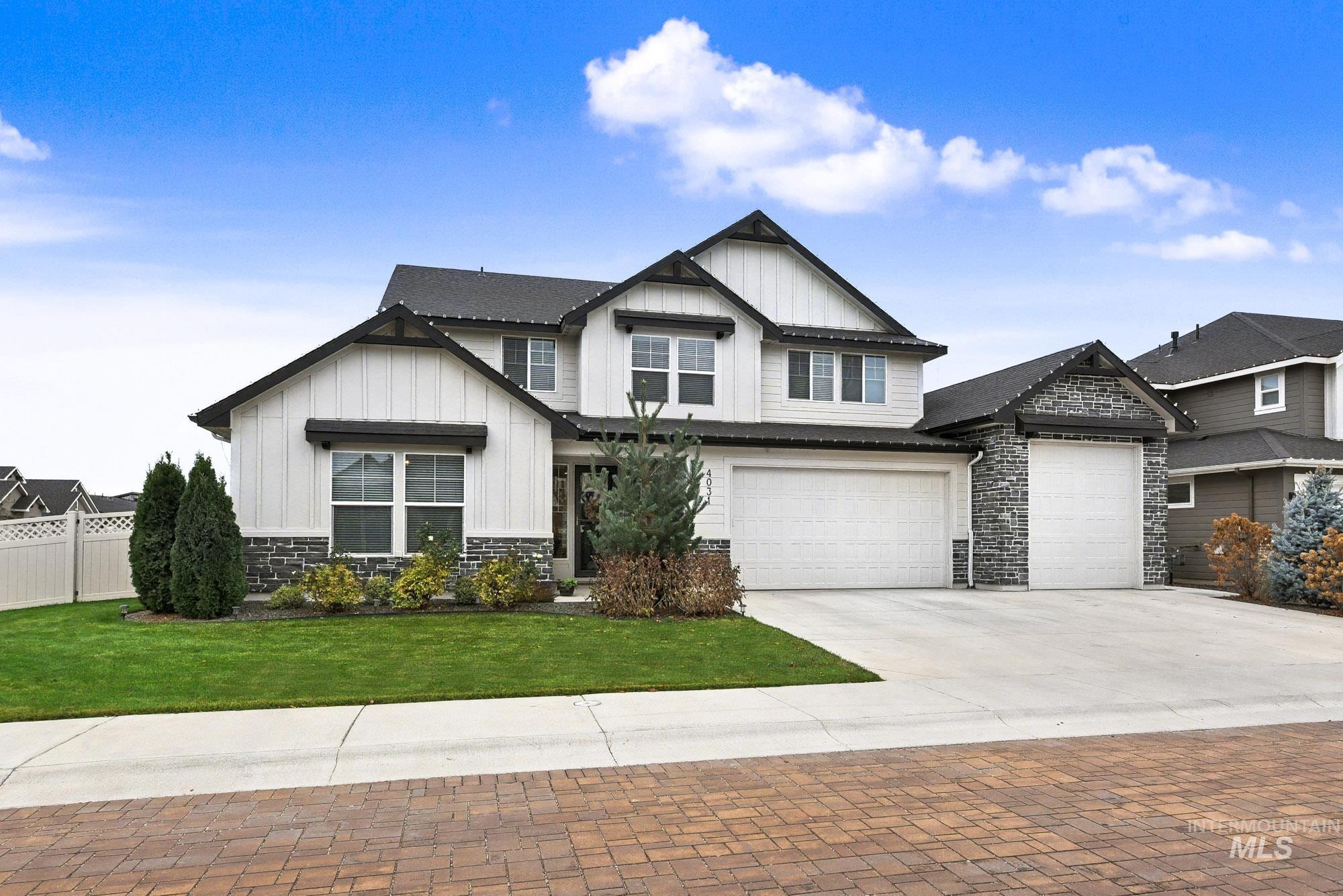 View of front of property with stone siding, board and batten siding, driveway, and a garage