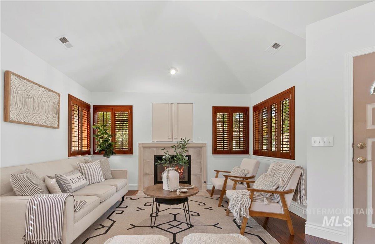 Living room with wood finished floors, a premium fireplace, and lofted ceiling