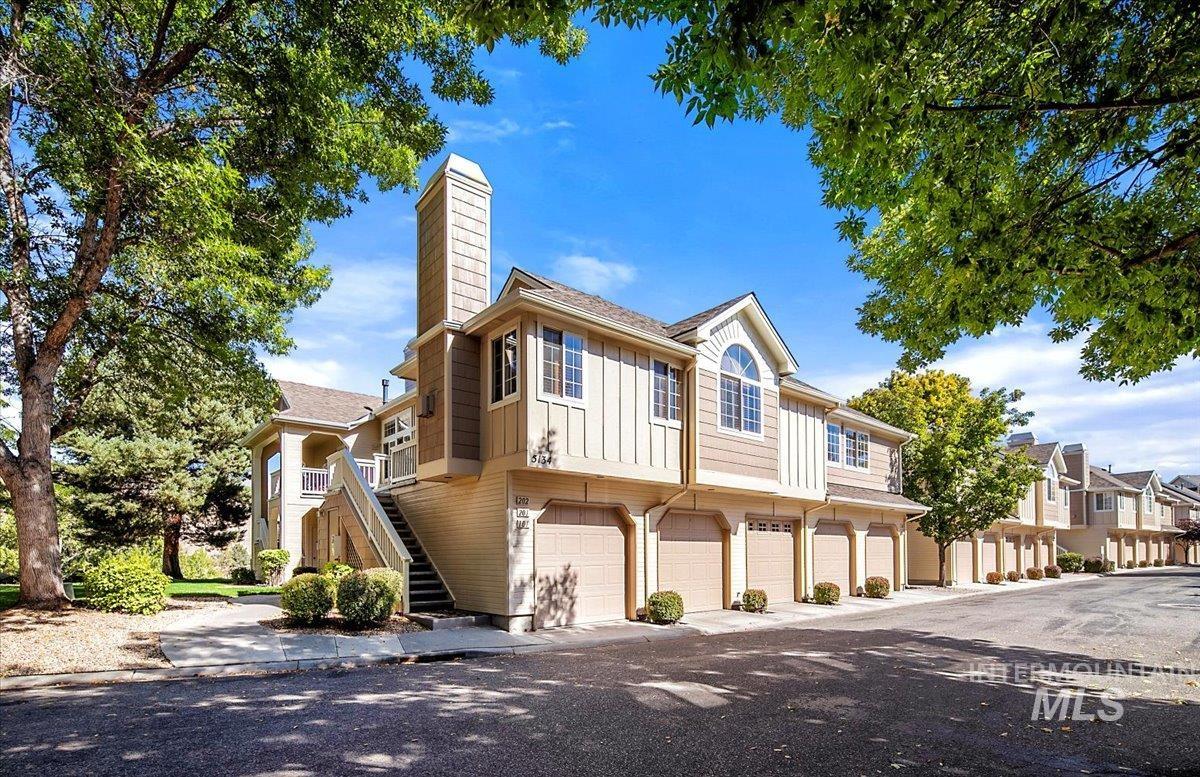 View of front facade with stairs, board and batten siding, a chimney, an attached garage, and a residential view