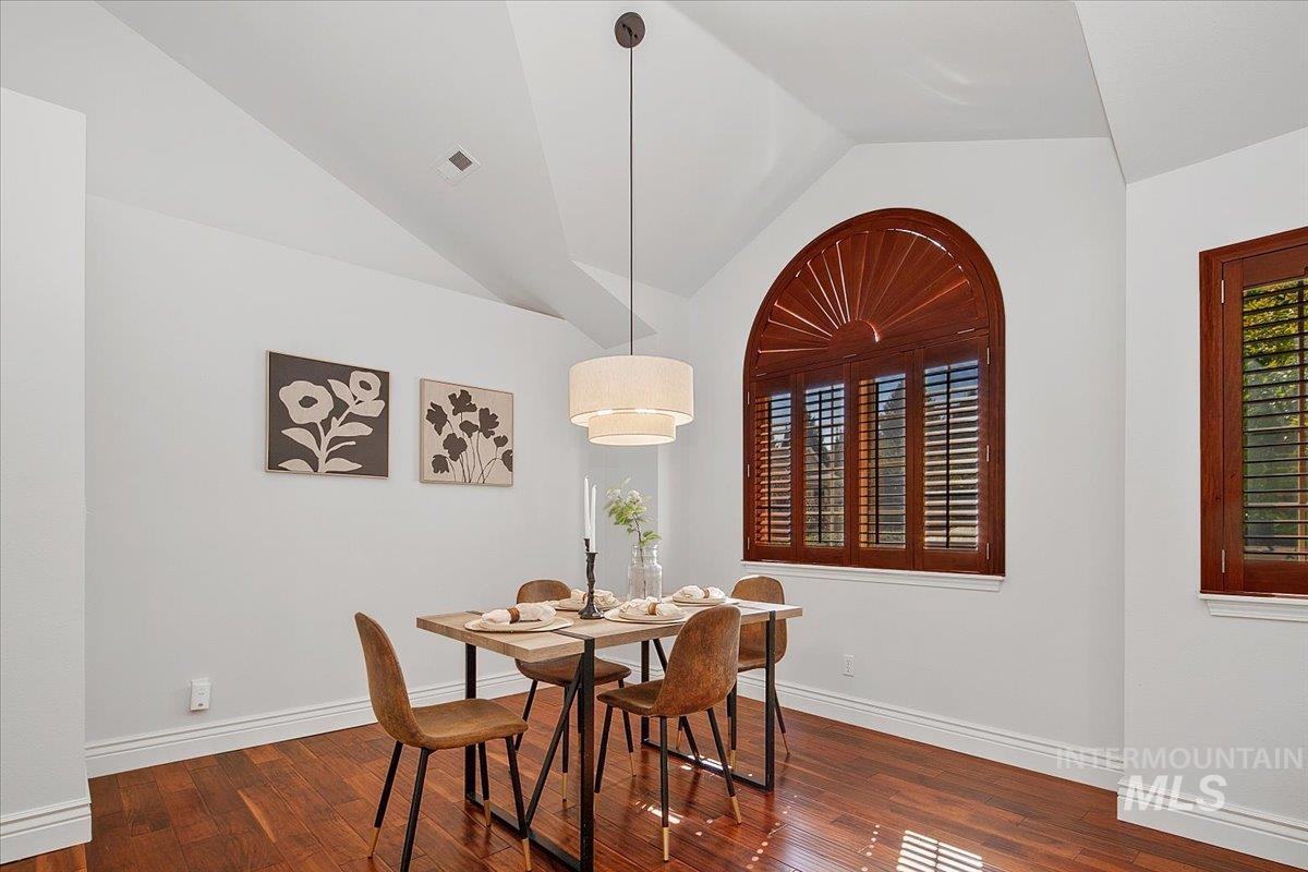 Dining room featuring vaulted ceiling and dark wood-style floors