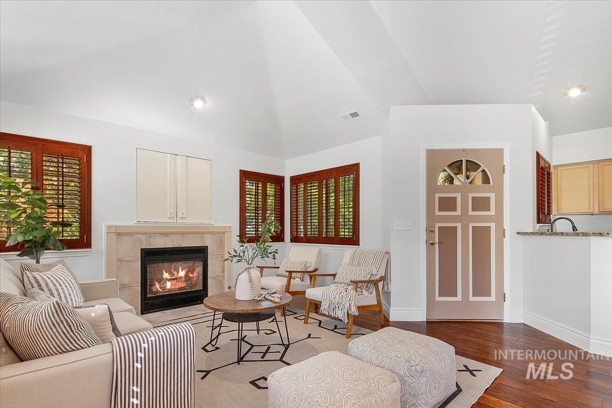 Living room with lofted ceiling, wood finished floors, a fireplace, and recessed lighting