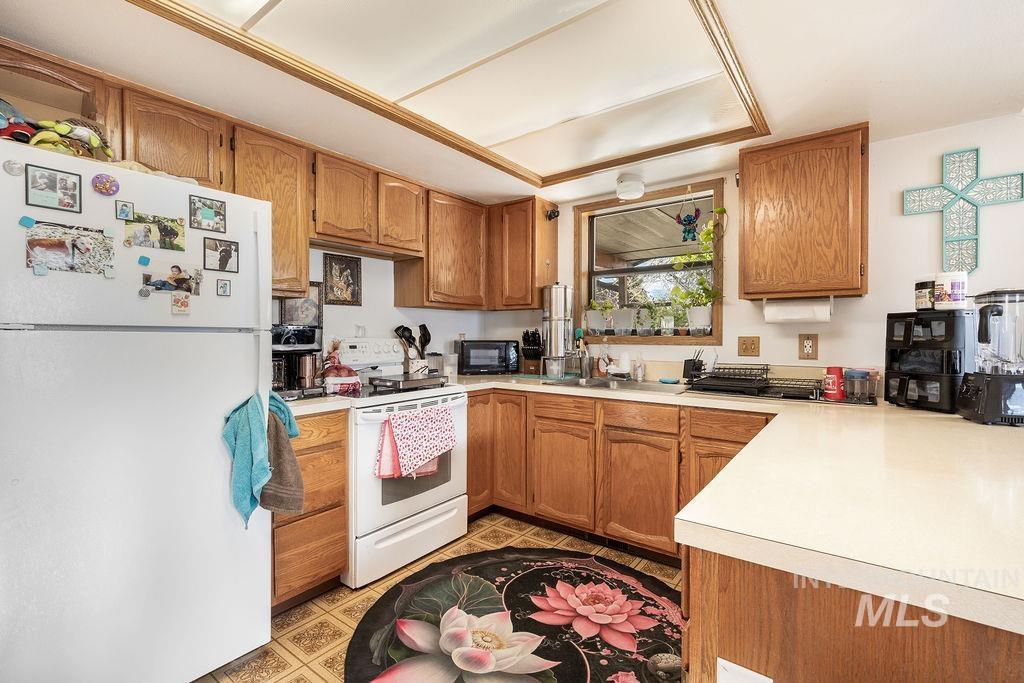 Kitchen with white appliances, light countertops, and wood finish cabinetry
