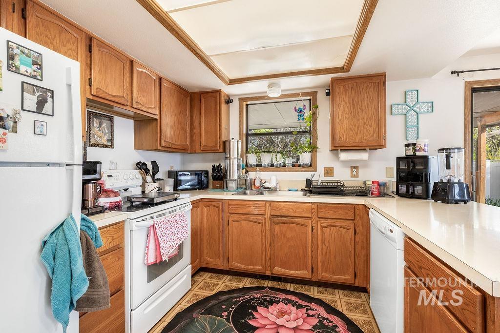 Kitchen with white appliances, wood finish cabinets, light countertops, and a peninsula