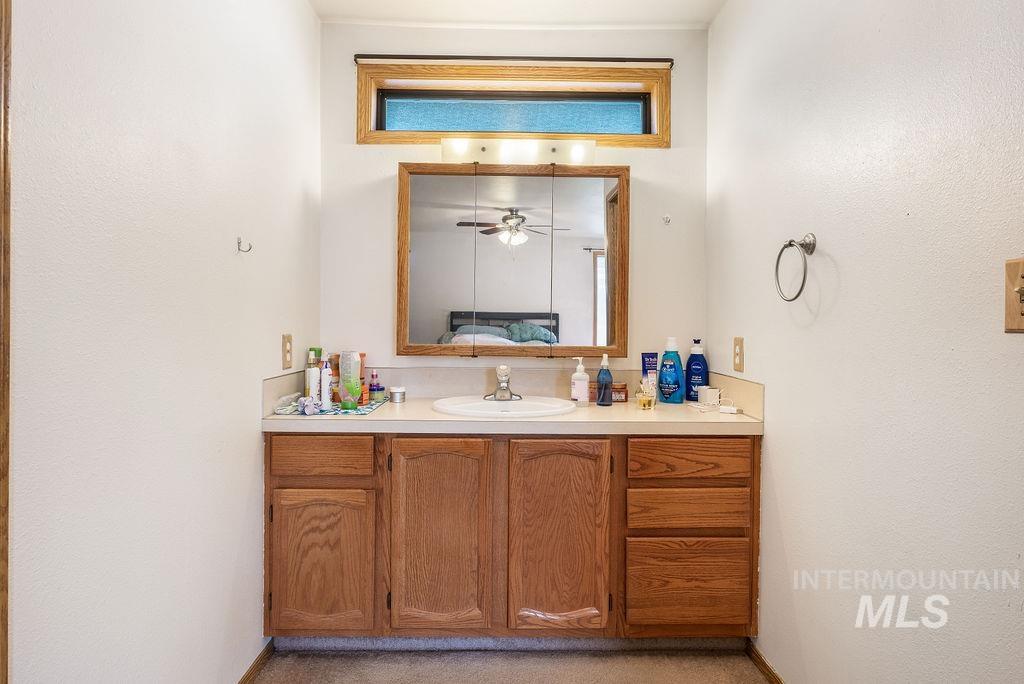 Bathroom featuring vanity, ceiling fan, and a textured wall