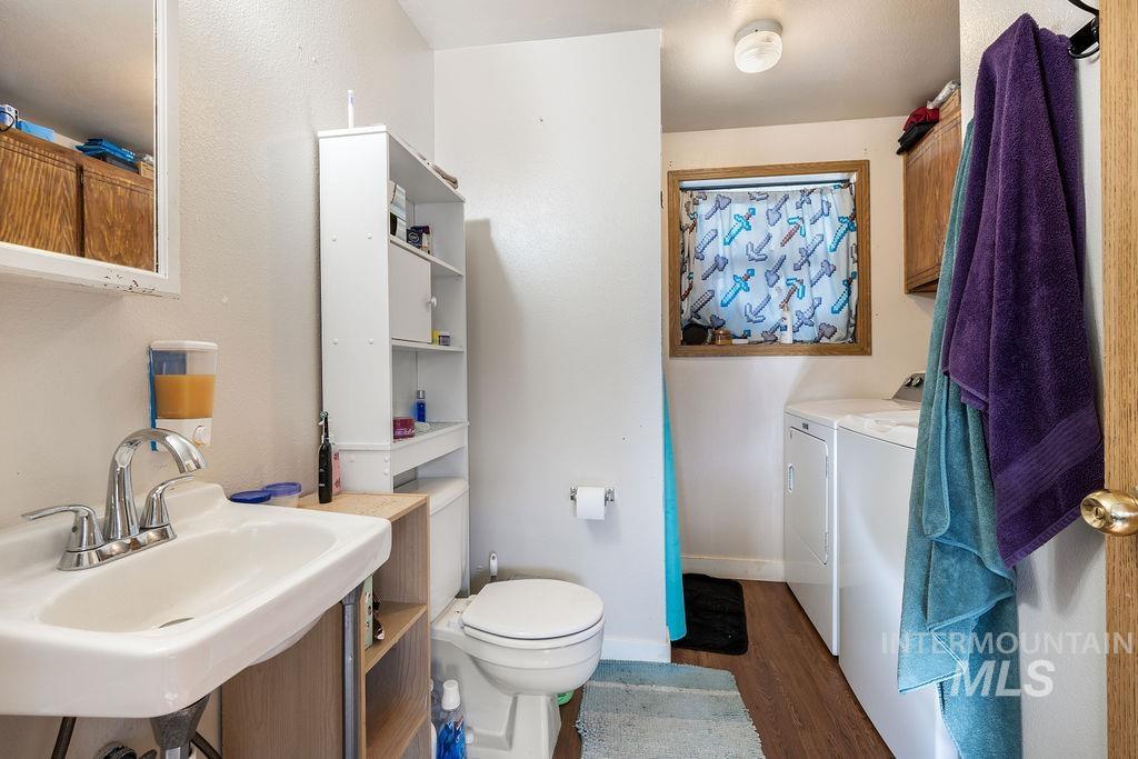 Half bath with dark wood-style flooring, independent washer and dryer, and vanity