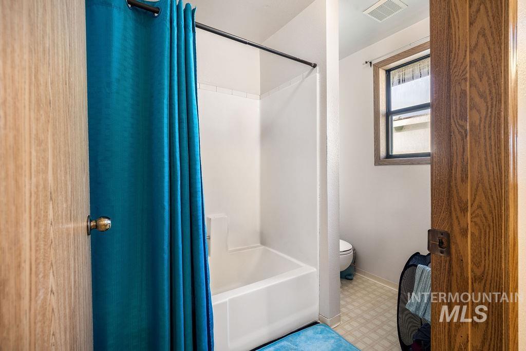 Full bath featuring light floors and shower / bathtub combination with curtain