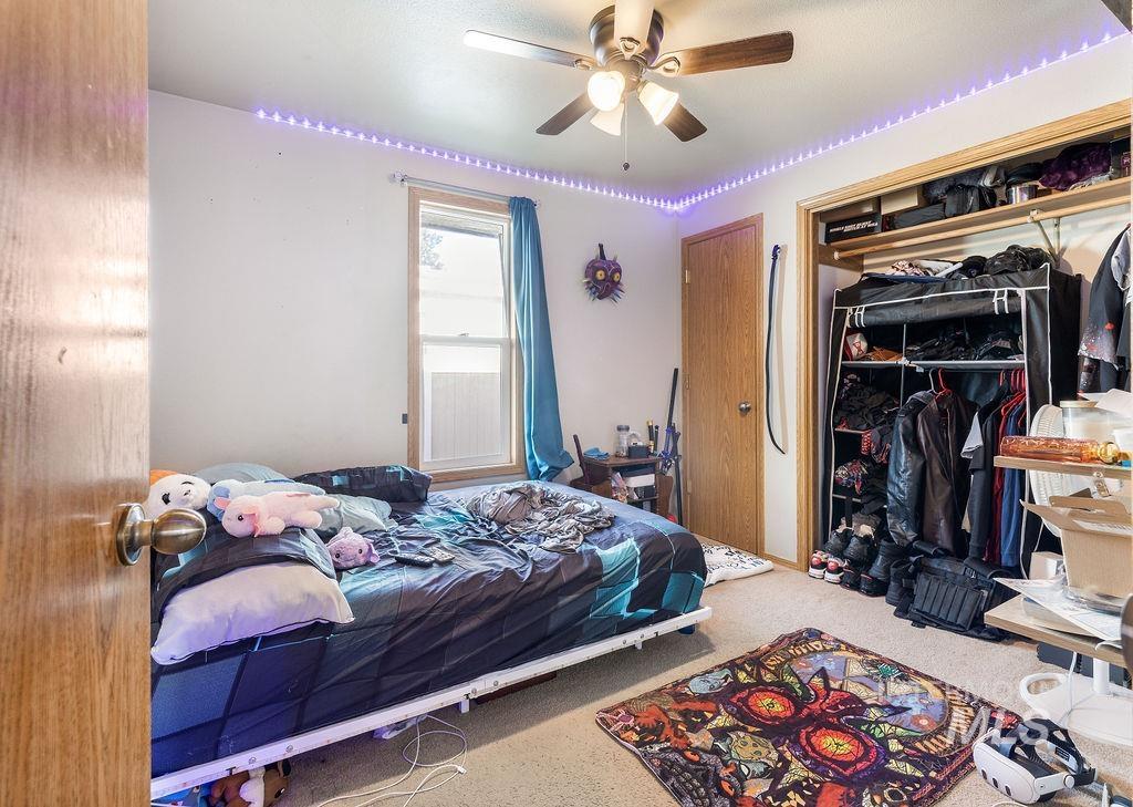 Carpeted bedroom with ceiling fan and a closet