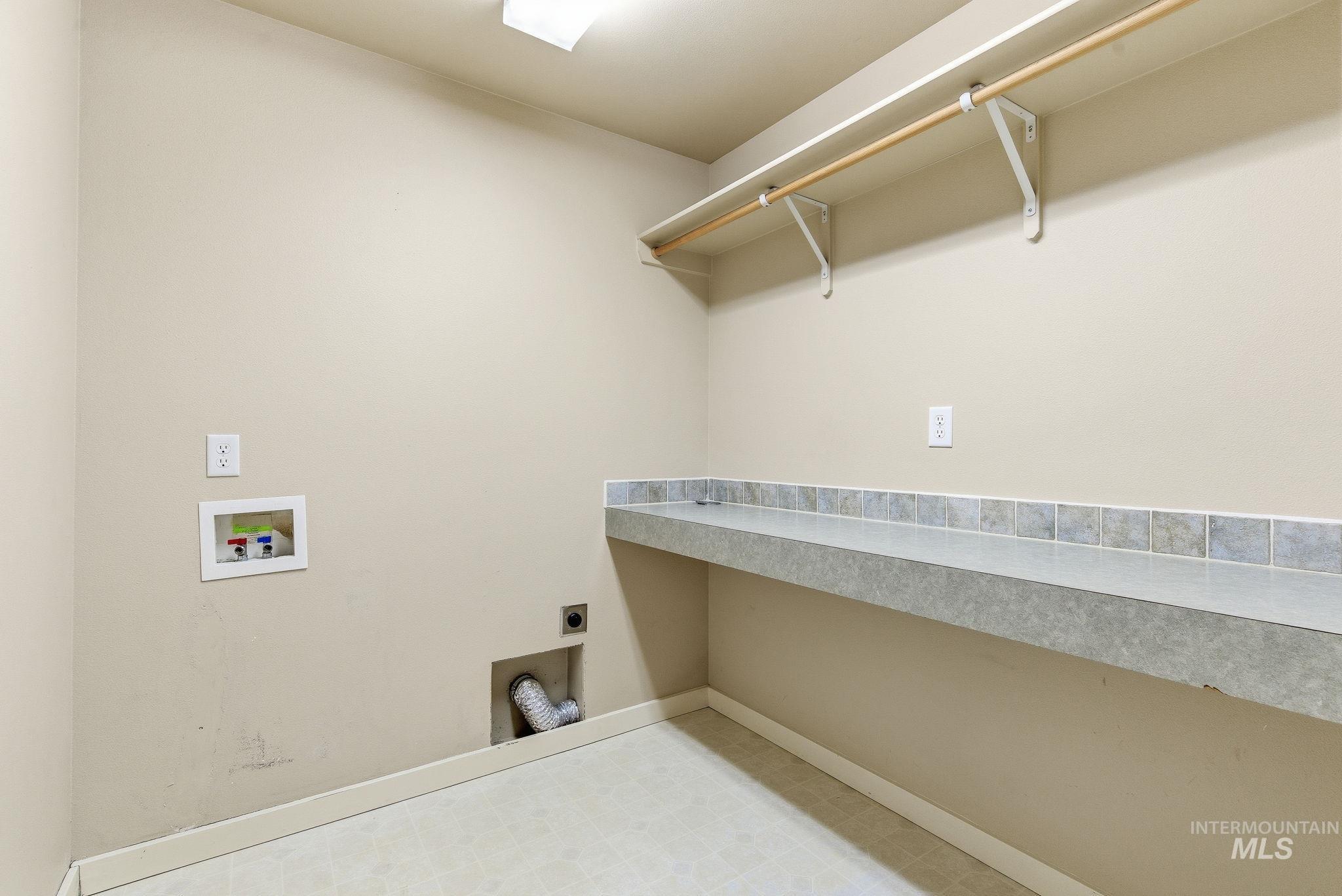 Washroom with electric dryer hookup, tile patterned floors, and washer hookup