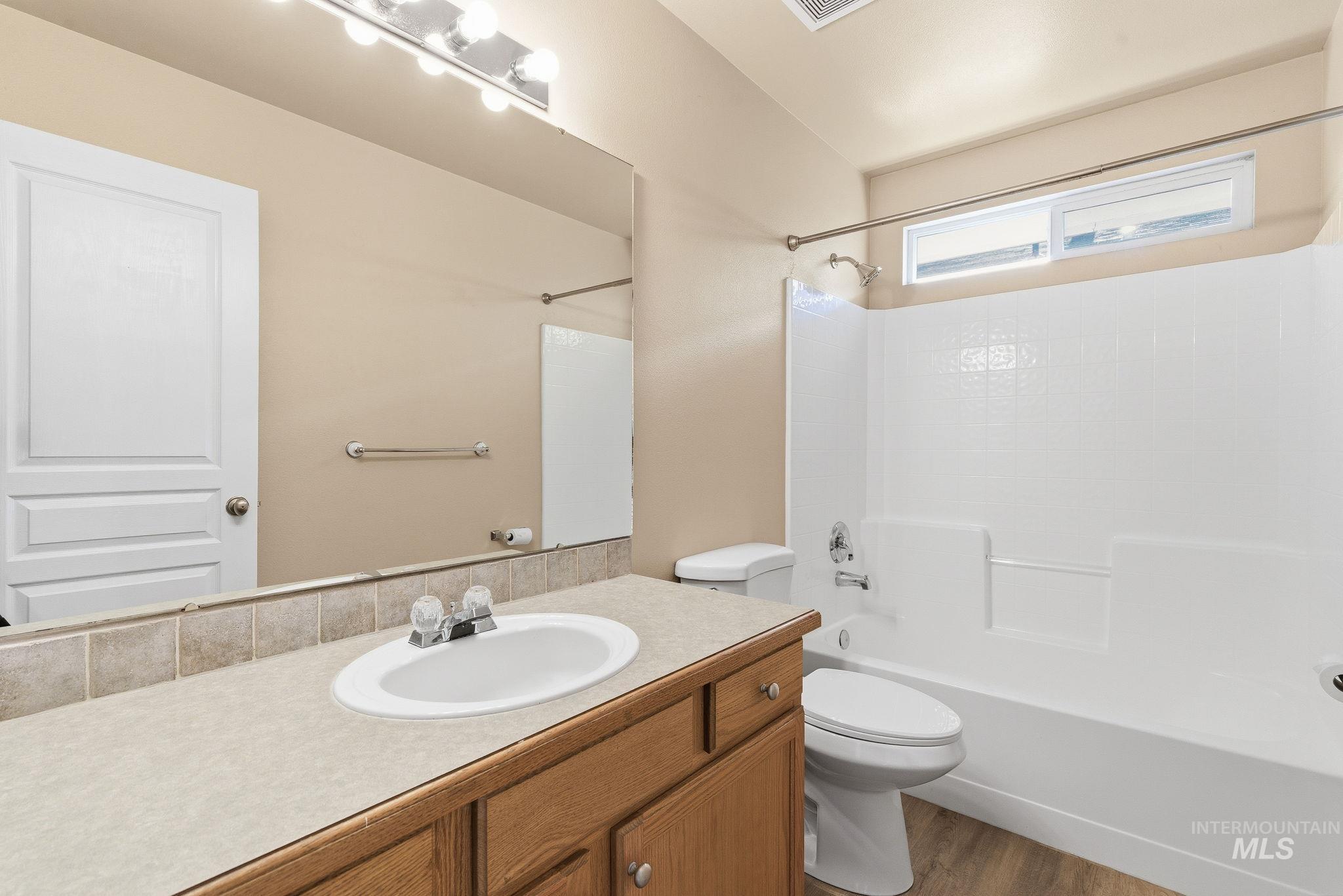 Bathroom featuring bathtub / shower combination, vanity, and dark wood-style floors