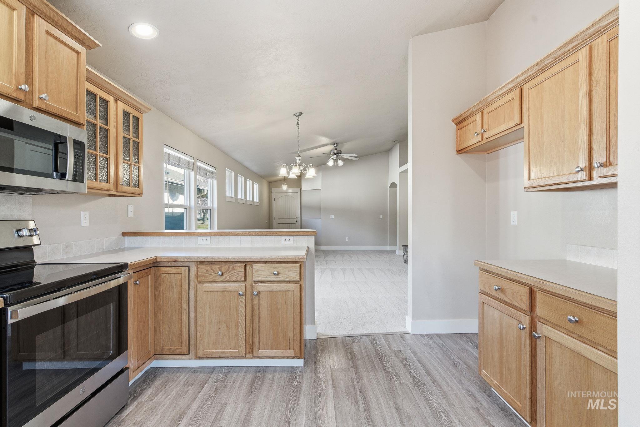 Kitchen with stainless steel appliances, light countertops, a peninsula, ceiling fan, and light brown cabinets