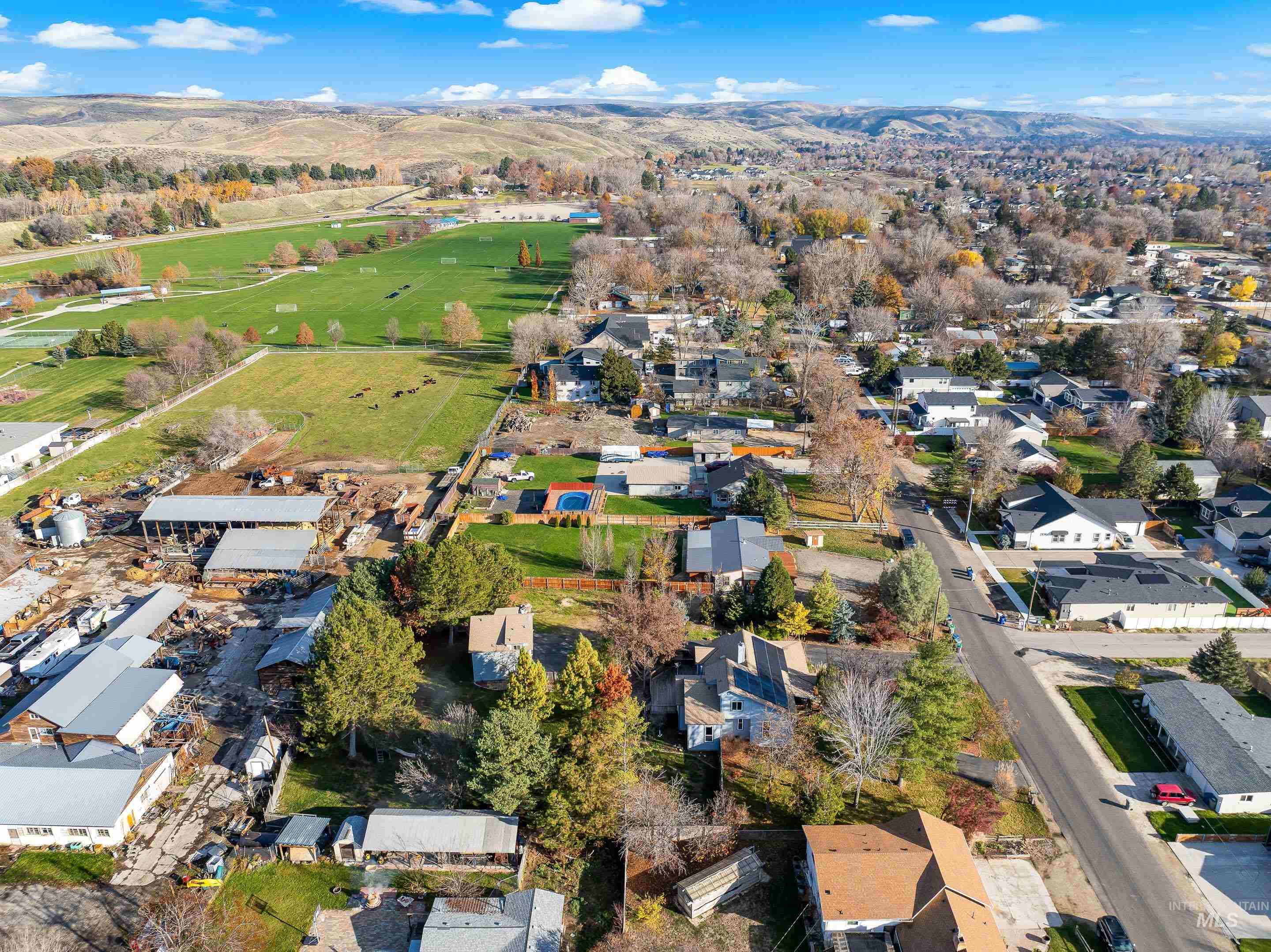 Aerial view of property and surrounding area featuring nearby suburban area and a mountainous background
