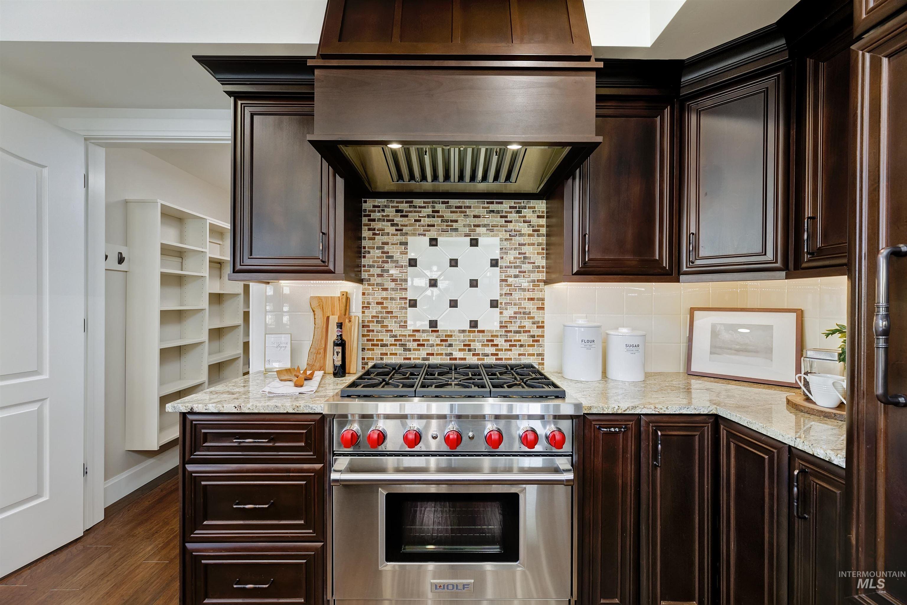 Kitchen with luxury range, exhaust hood, light stone countertops, and tasteful backsplash