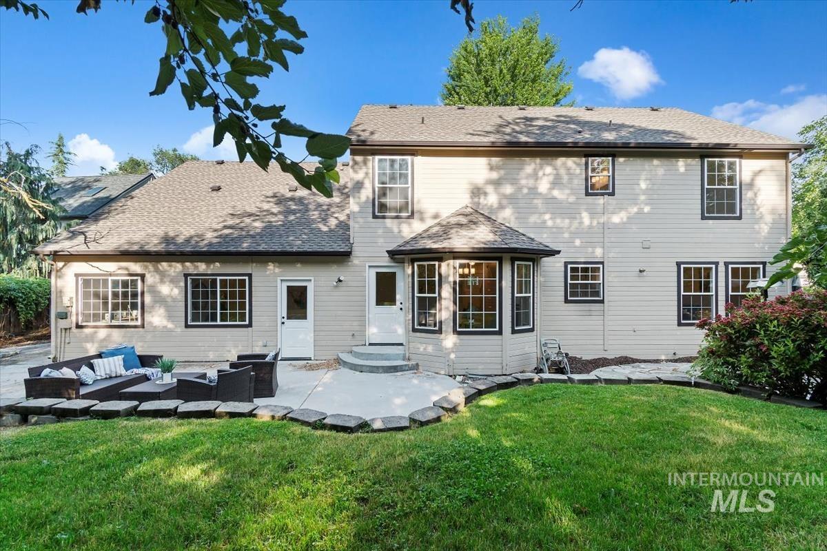 Rear view of house featuring a patio area, an outdoor living space, a lawn, and roof with shingles