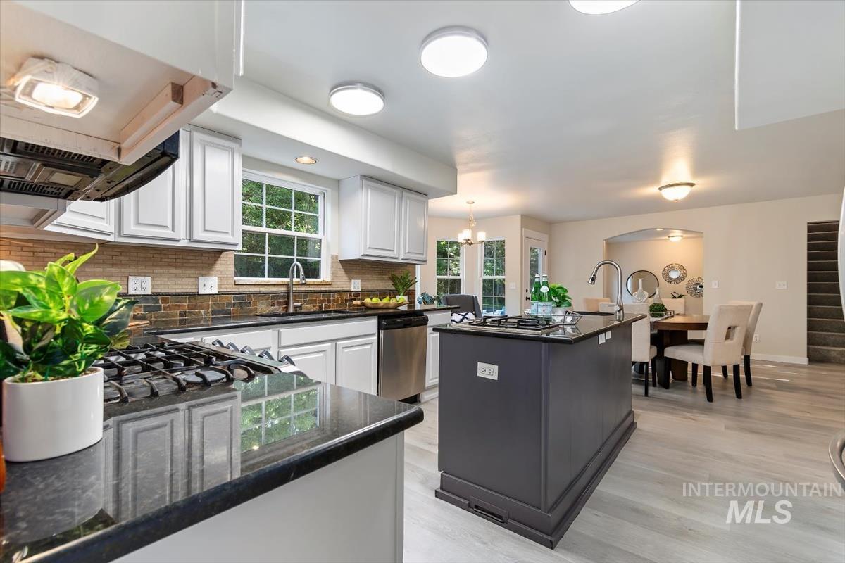 Kitchen featuring stainless steel appliances, a center island, tasteful backsplash, white cabinetry, and arched walkways