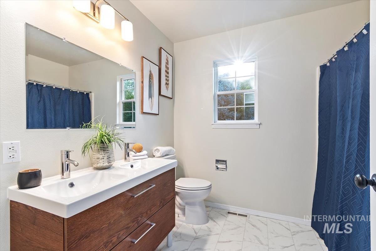 Bathroom with vanity, marble look tiles, and curtained shower