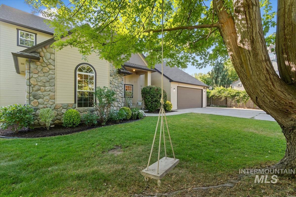 View of front of property featuring stone siding, driveway, and an attached garage