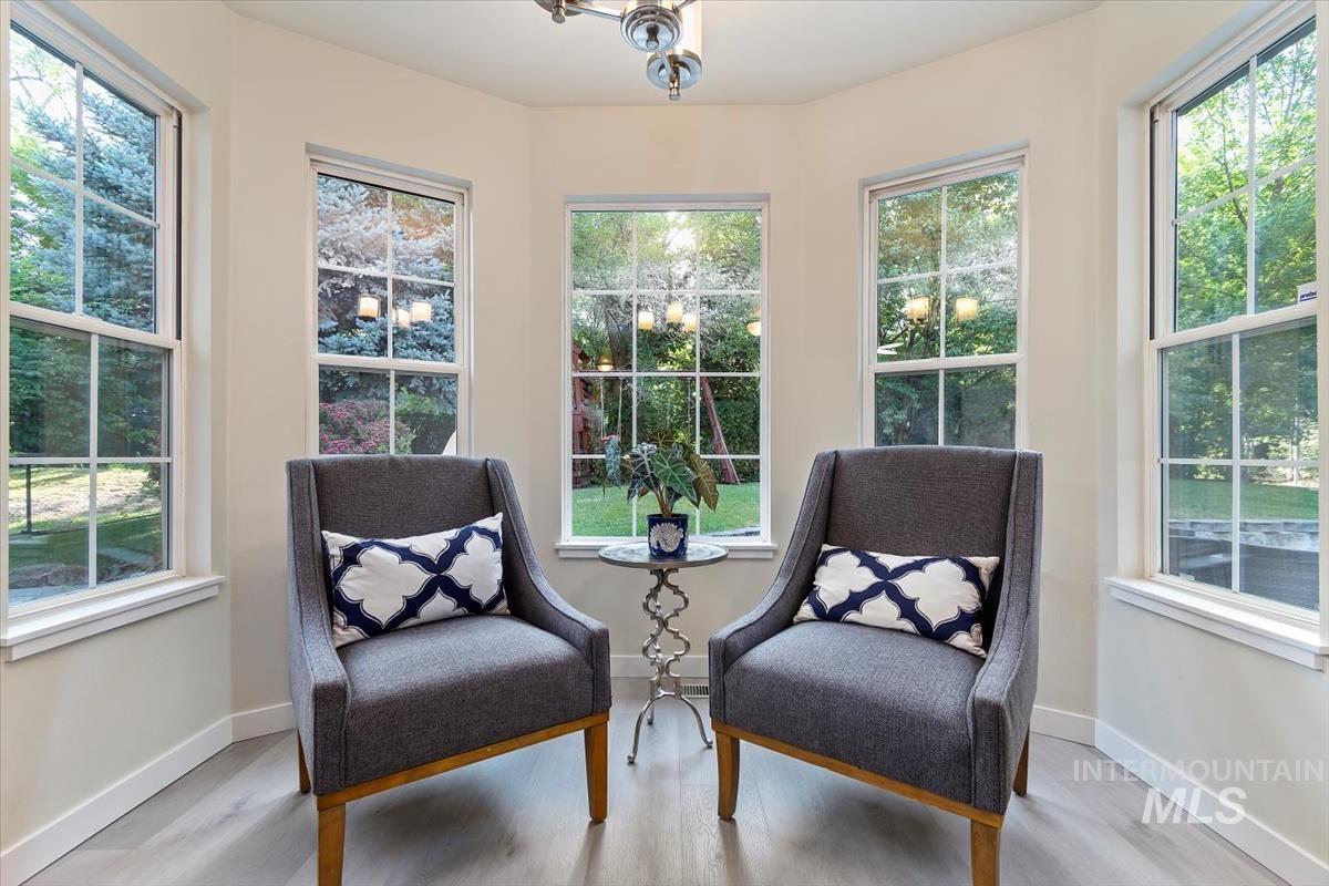 Living area with healthy amount of natural light, light wood finished floors, and a chandelier
