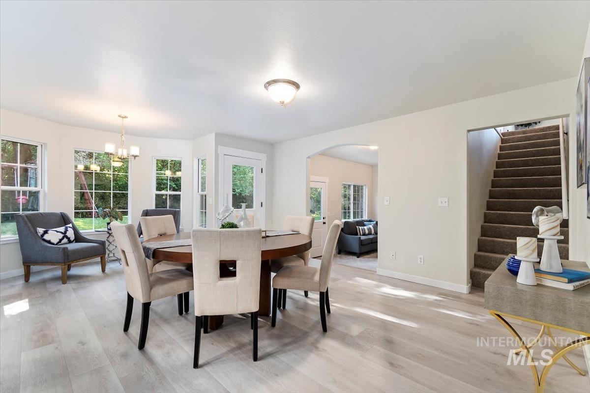 Dining room with light wood finished floors, arched walkways, stairway, and a chandelier