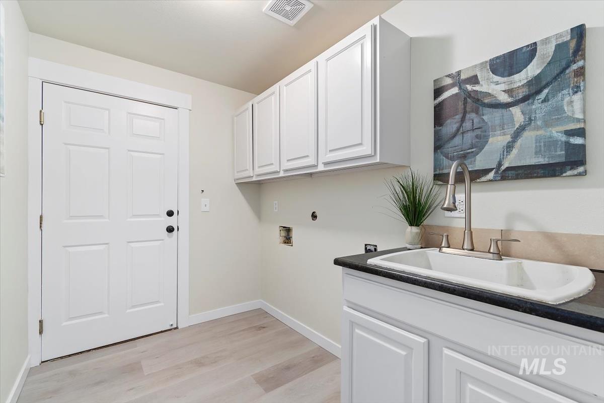 Laundry room with hookup for a washing machine, light wood finished floors, and cabinet space