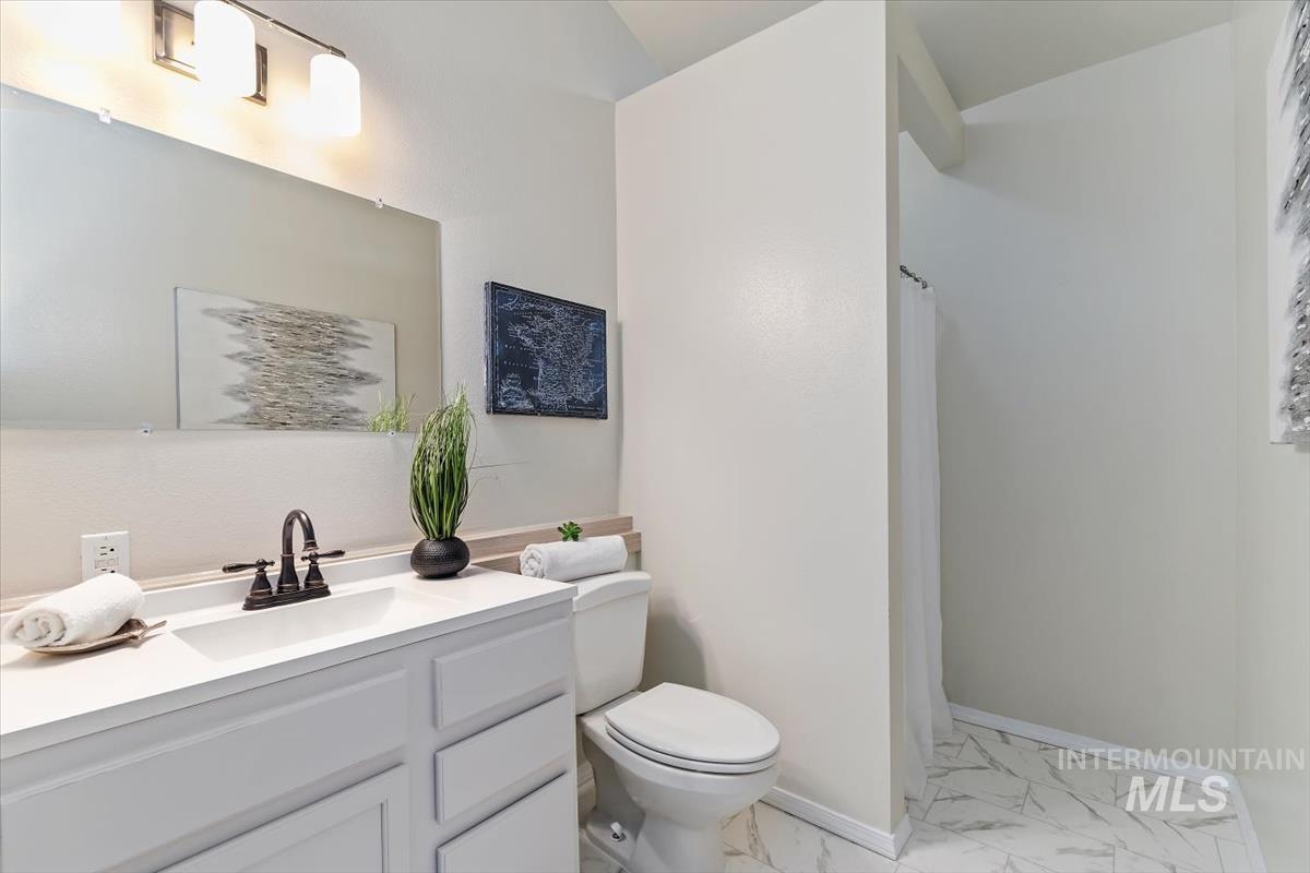 Full bath featuring marble finish flooring, vanity, and curtained shower