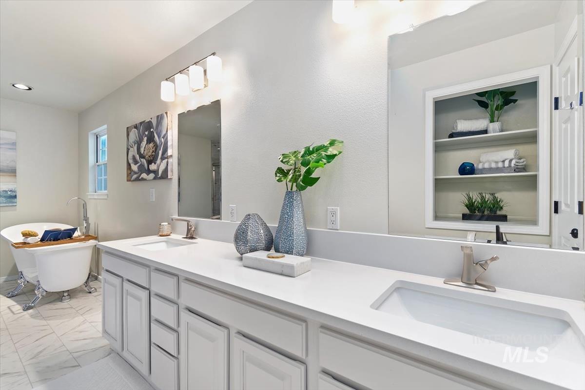 Full bath featuring double vanity, a freestanding bath, marble finish flooring, and recessed lighting