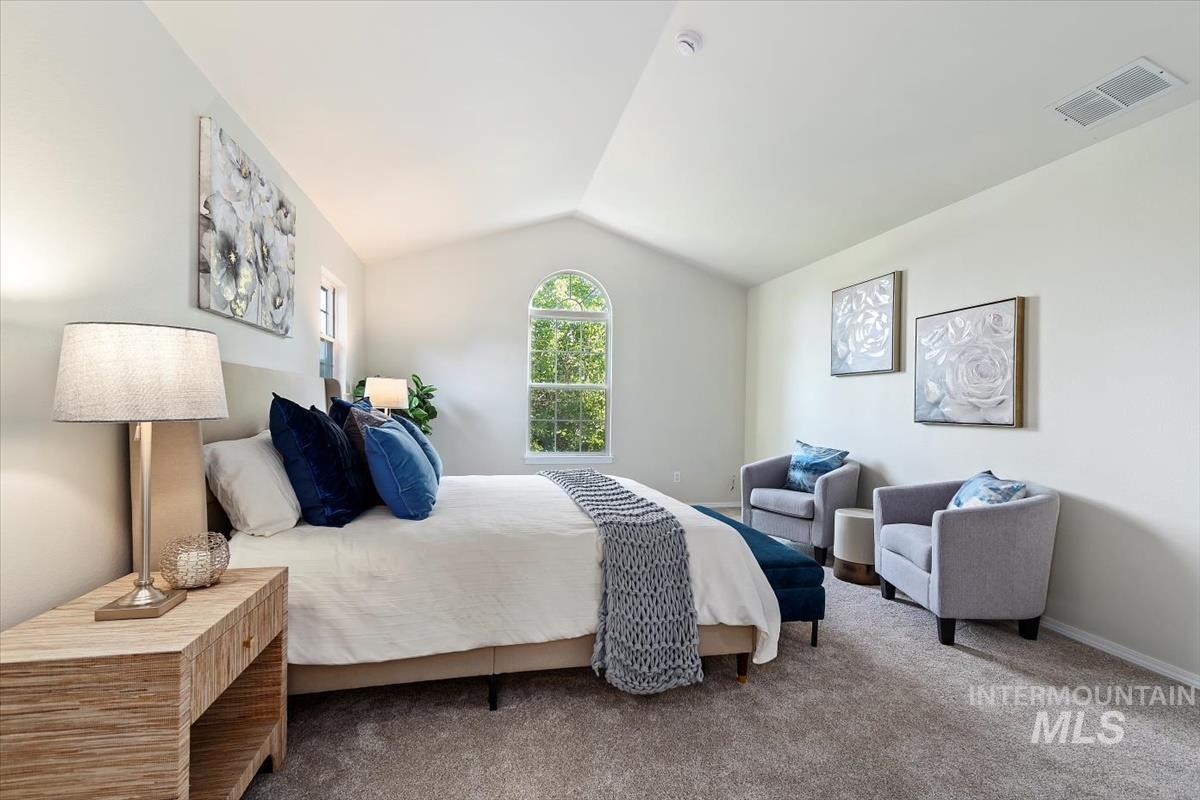 Carpeted bedroom featuring vaulted ceiling and ensuite bath and slipper tub