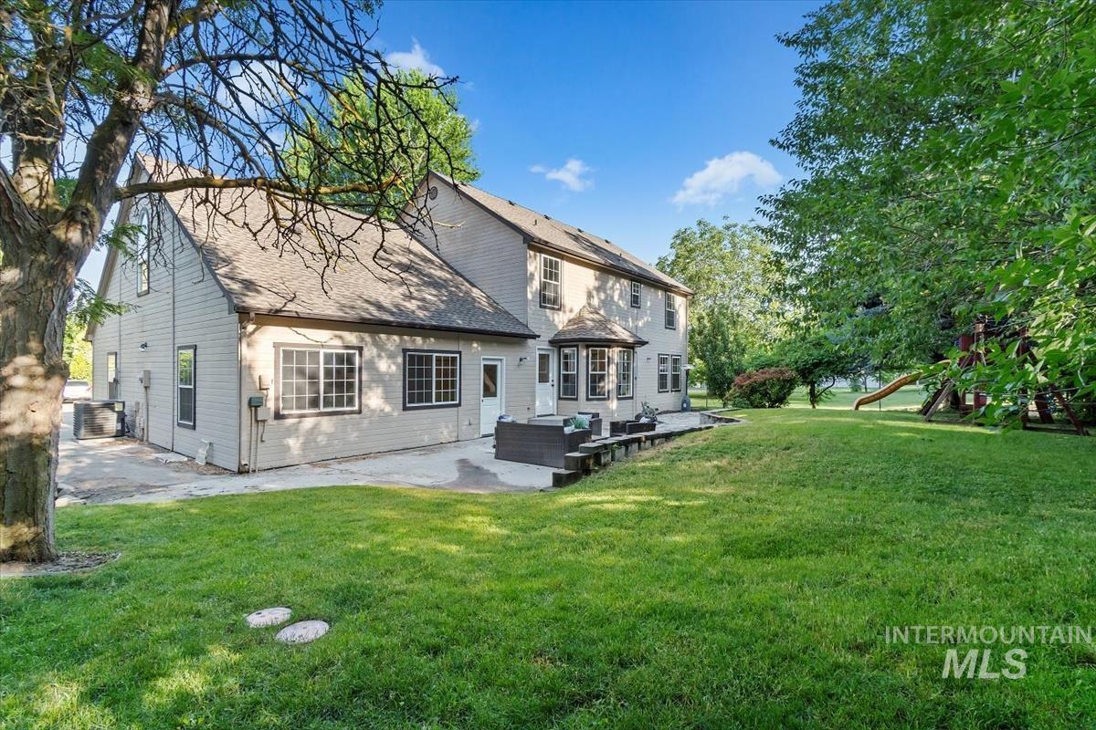 Back of house with an outdoor living space, a patio, a lawn, and a playground