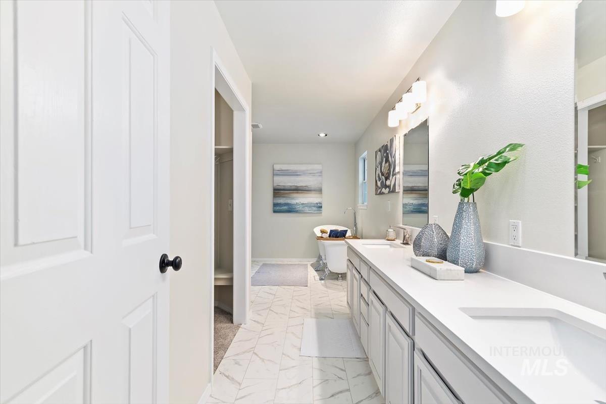 Bathroom with marble finish flooring, double vanity, and recessed lighting