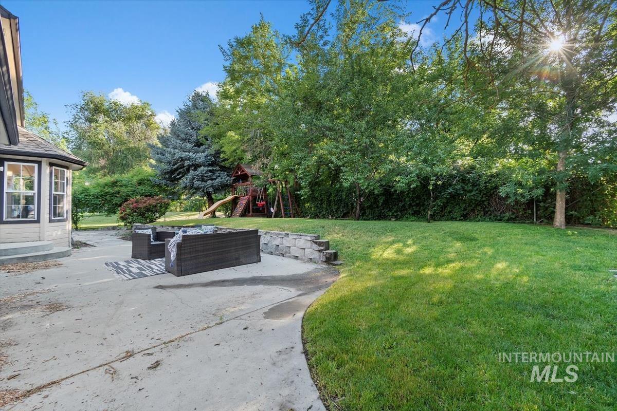 View of grassy yard featuring a playground, a patio, outdoor lounge area, and view of wooded area