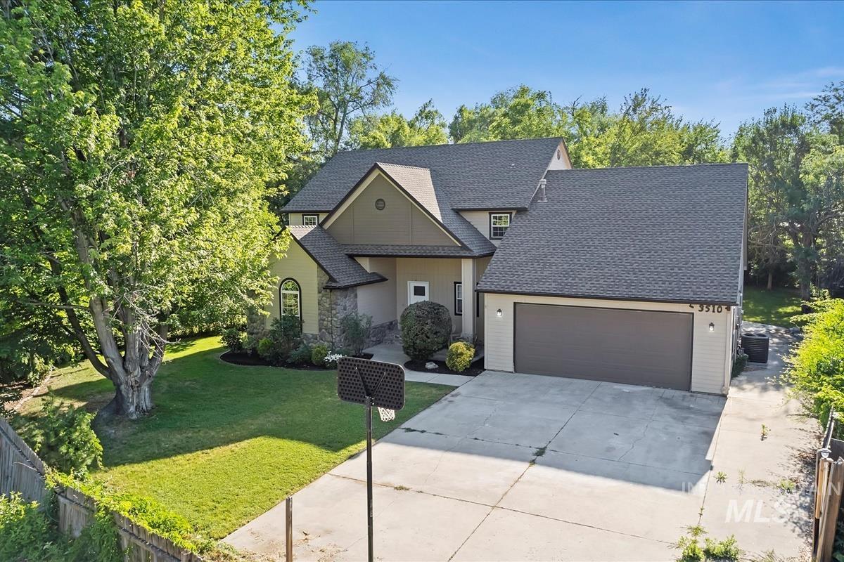 View of front facade with driveway, roof with shingles, and an attached garage