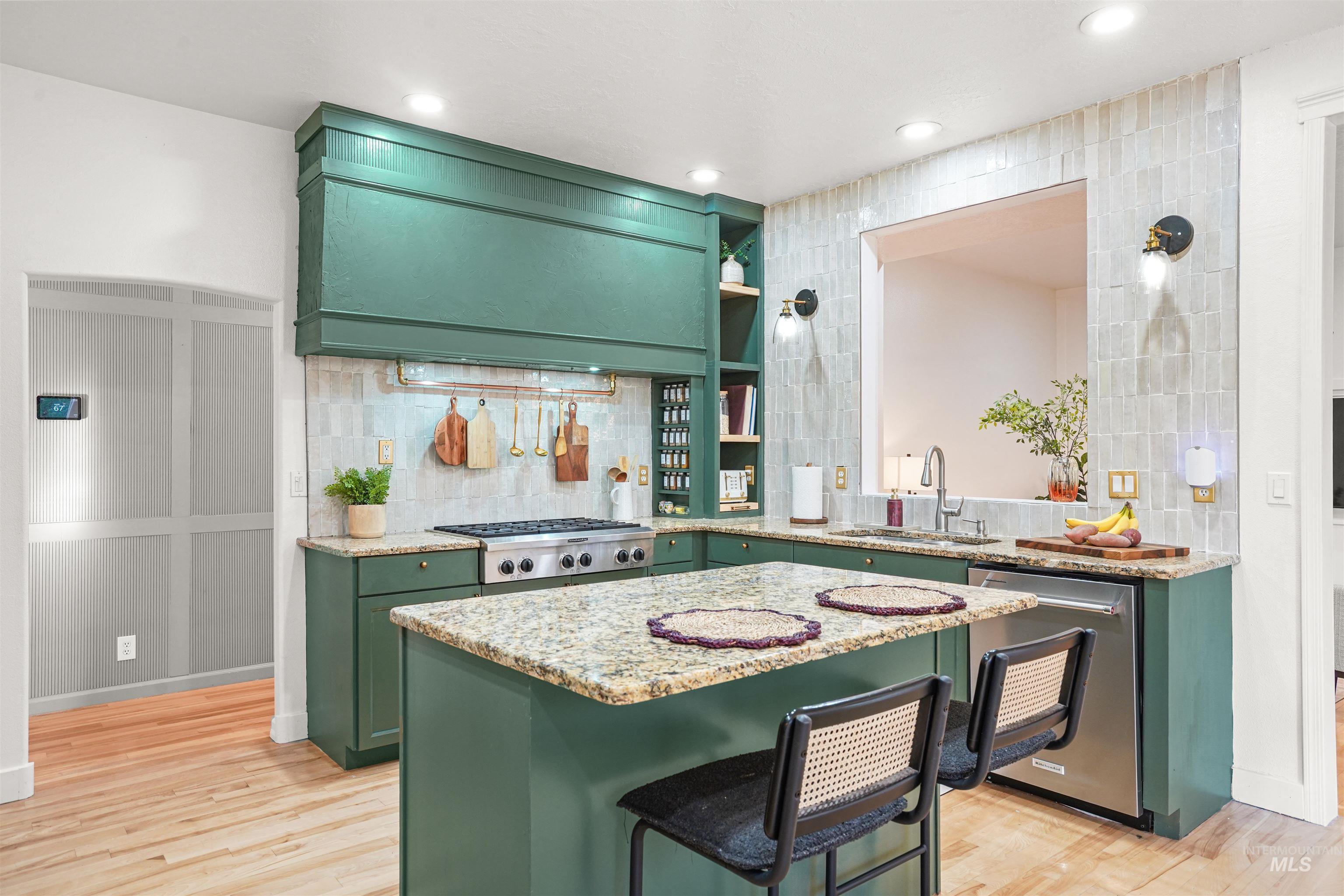 Kitchen with green cabinets, light stone counters, stainless steel appliances, light wood-style floors, and recessed lighting