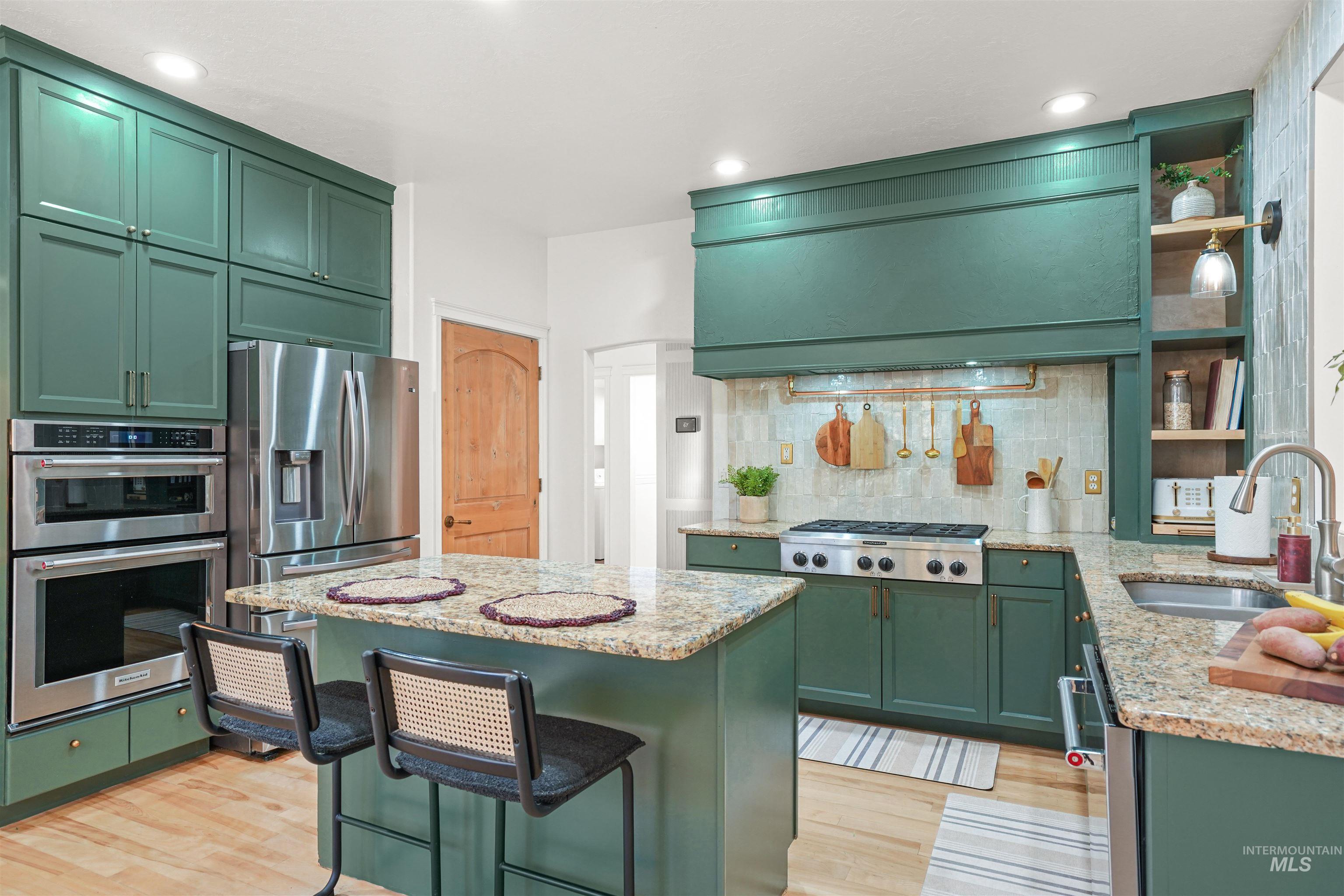 Kitchen with green cabinetry, light stone countertops, open shelves, and recessed lighting