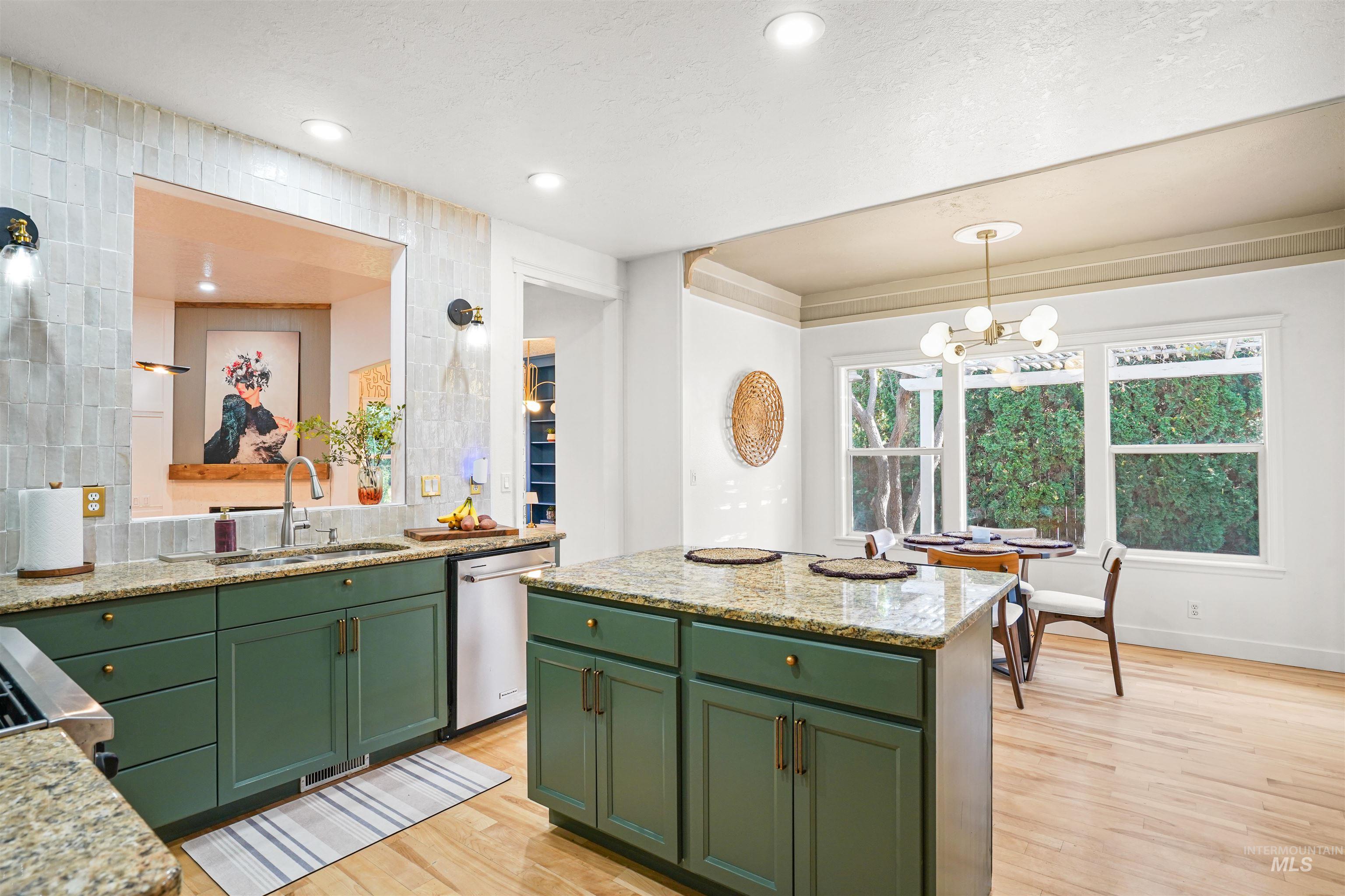 Kitchen with light stone countertops, light wood finished floors, green cabinetry, a center island, and recessed lighting