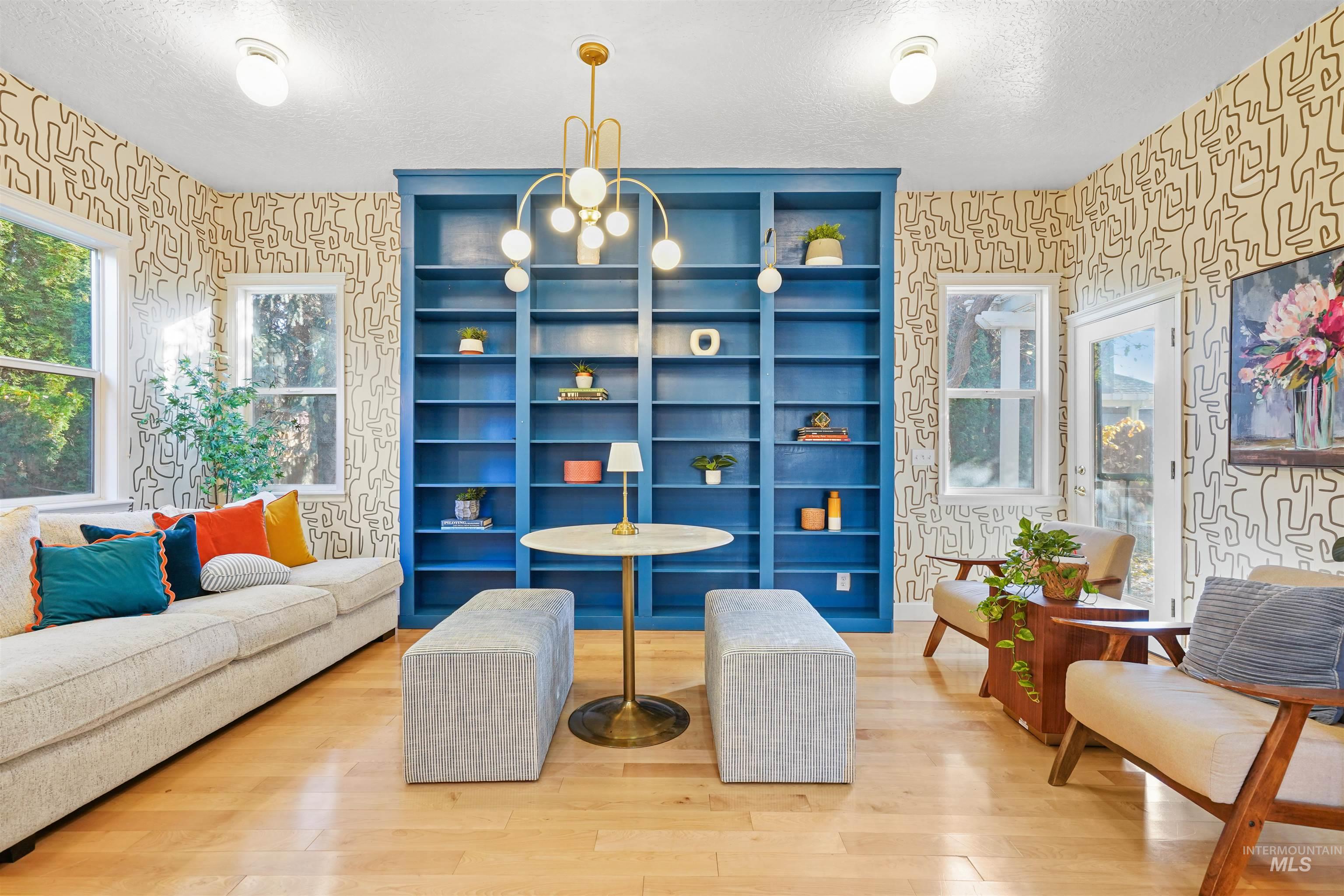 Living area with wallpapered walls, healthy amount of natural light, wood finished floors, a textured ceiling, and a chandelier