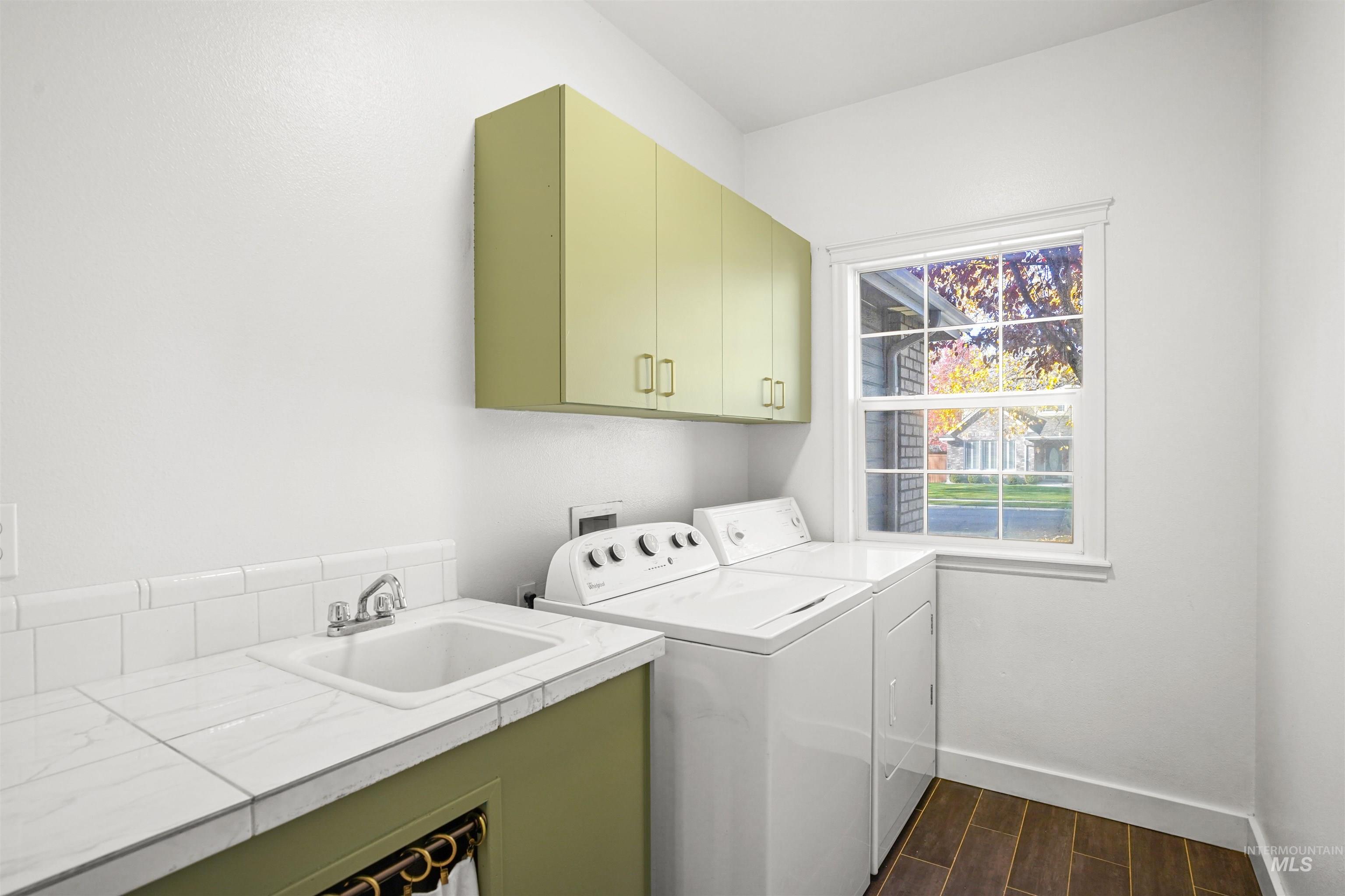 Laundry room featuring wood tiled floors, washing machine and dryer, and cabinet space