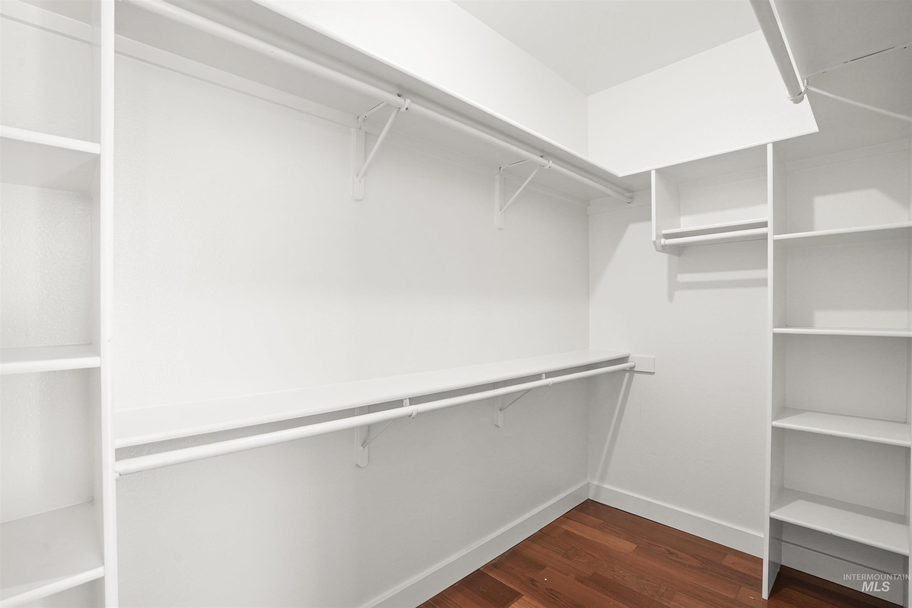 Walk in closet with dark wood-style floors